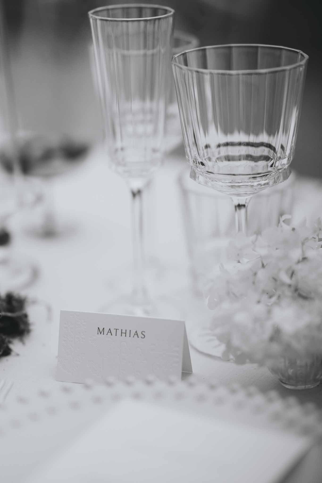Table name card alongside floral centerpiece and crystal glasses