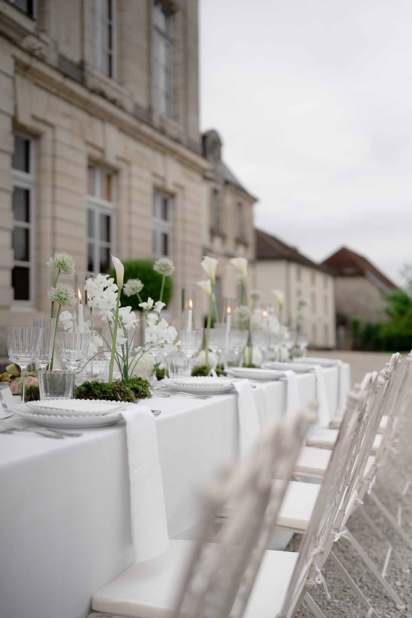 Reception tablescape with white chairs and organic floral centerpiece