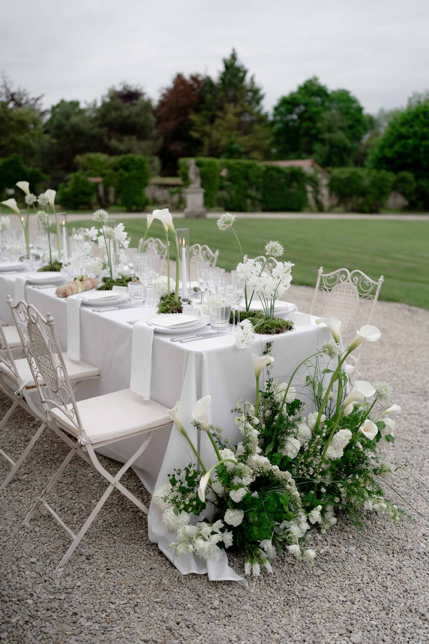 Reception table set with modern white steel chairs and floral arrangements
