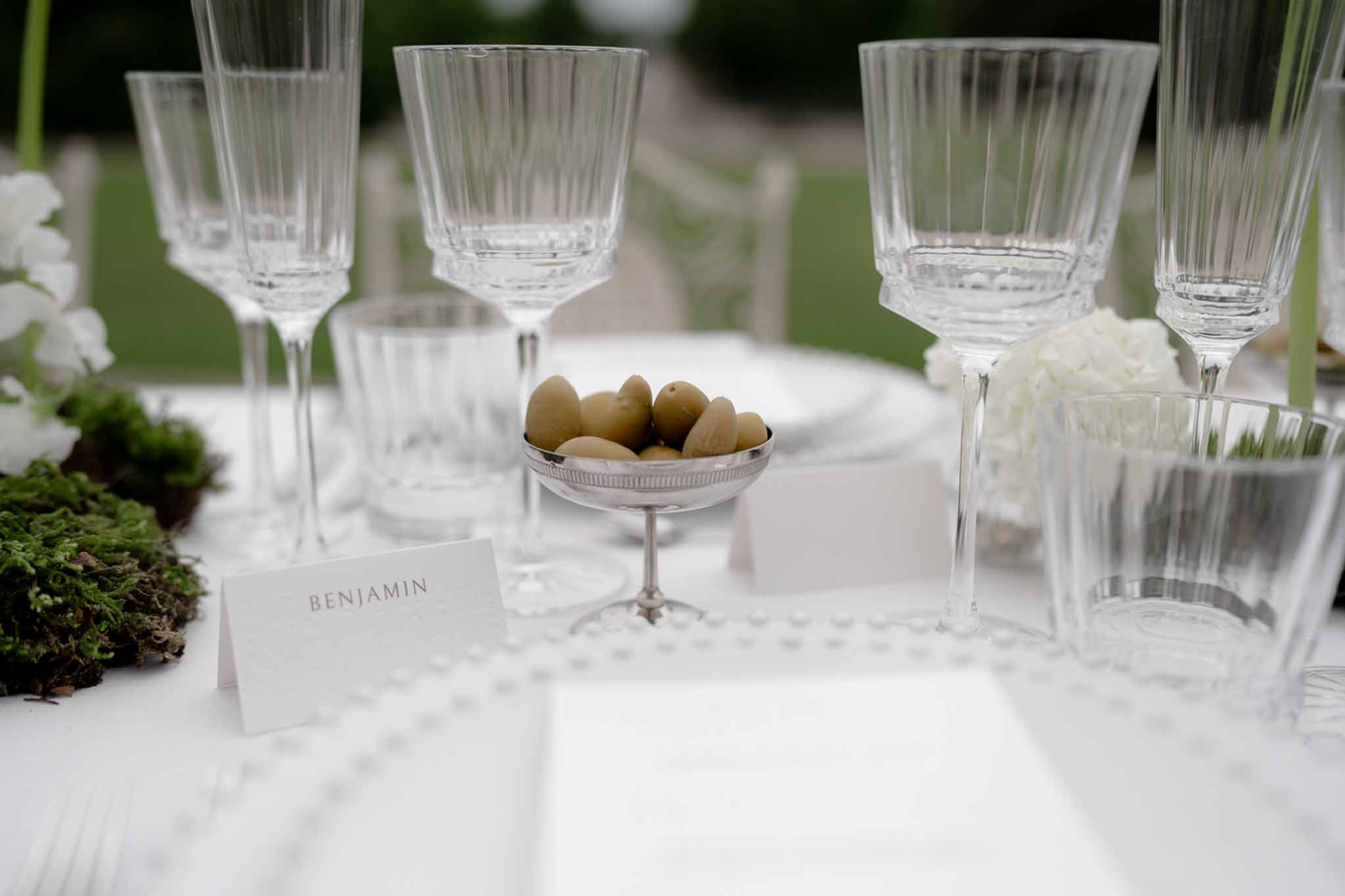 Table setting detail with crystal glasses, silver cup, and plated food