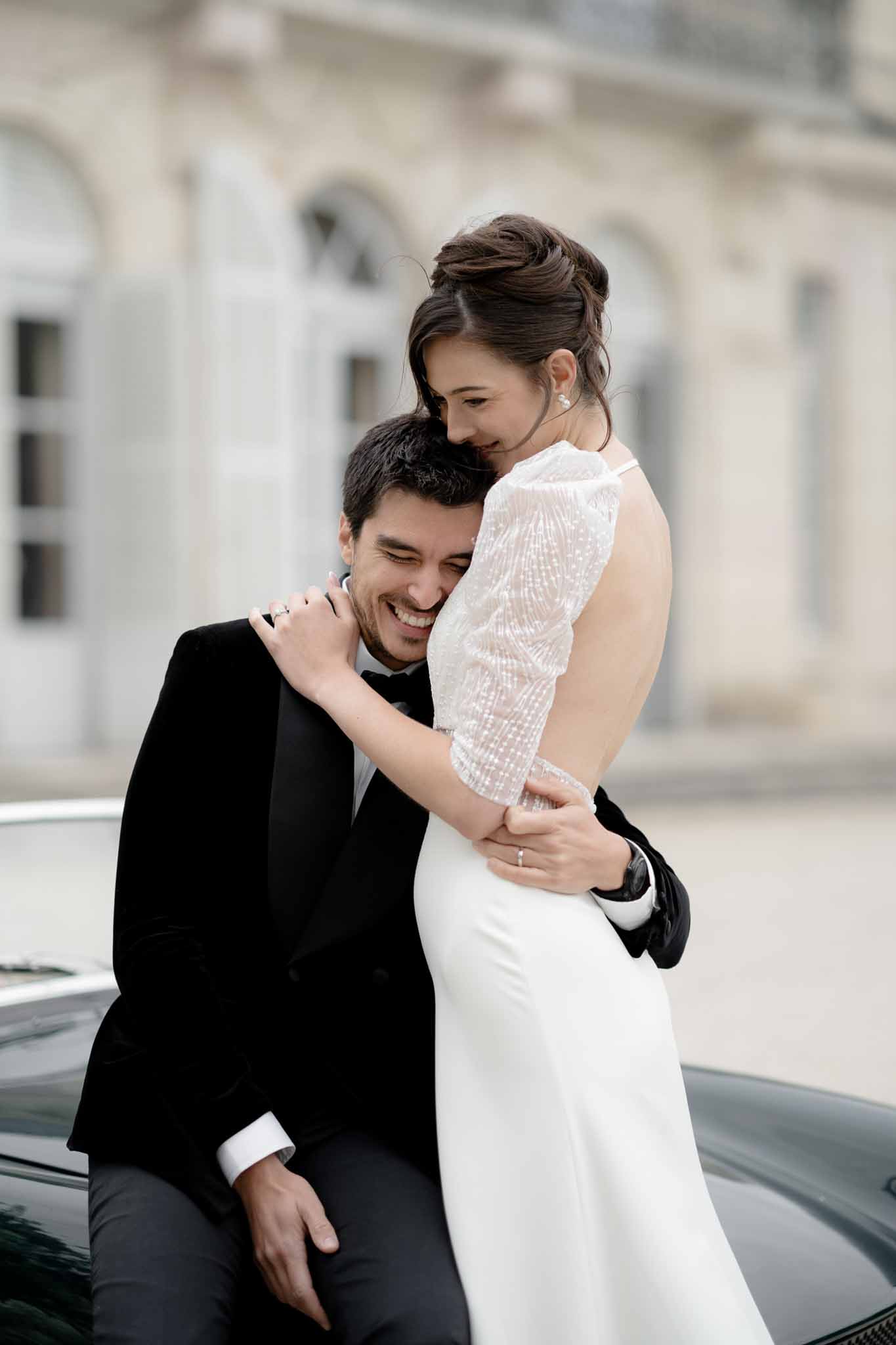Couple embracing beside a black vintage car at Chateau d'Arcelot