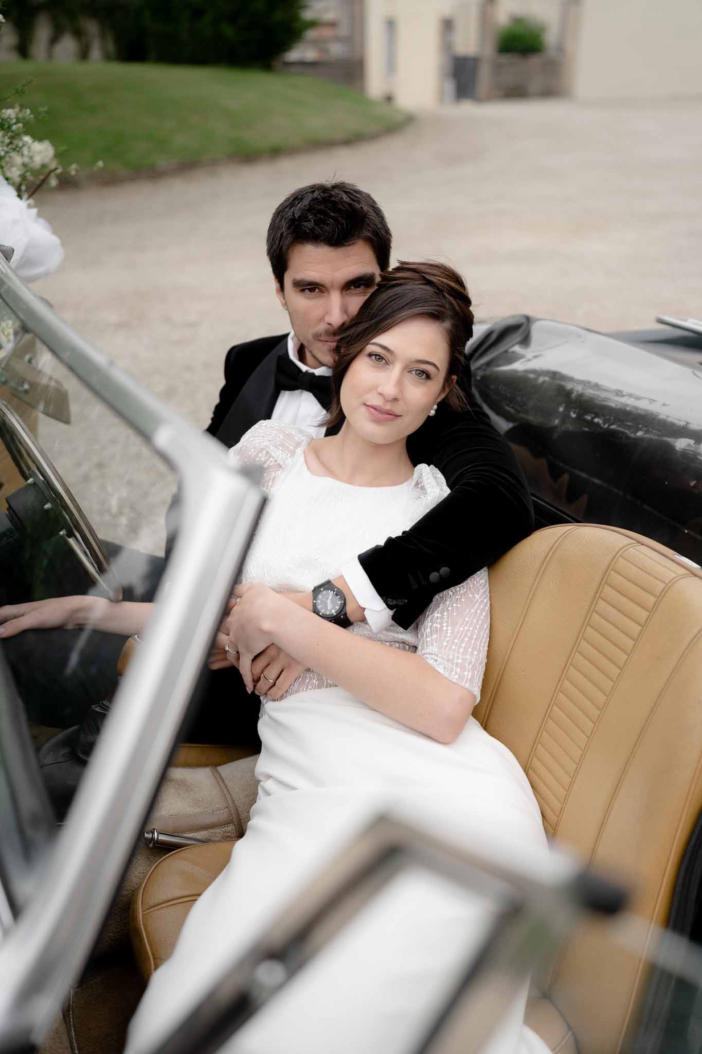 Couple seated together inside the vintage car in a tender moment