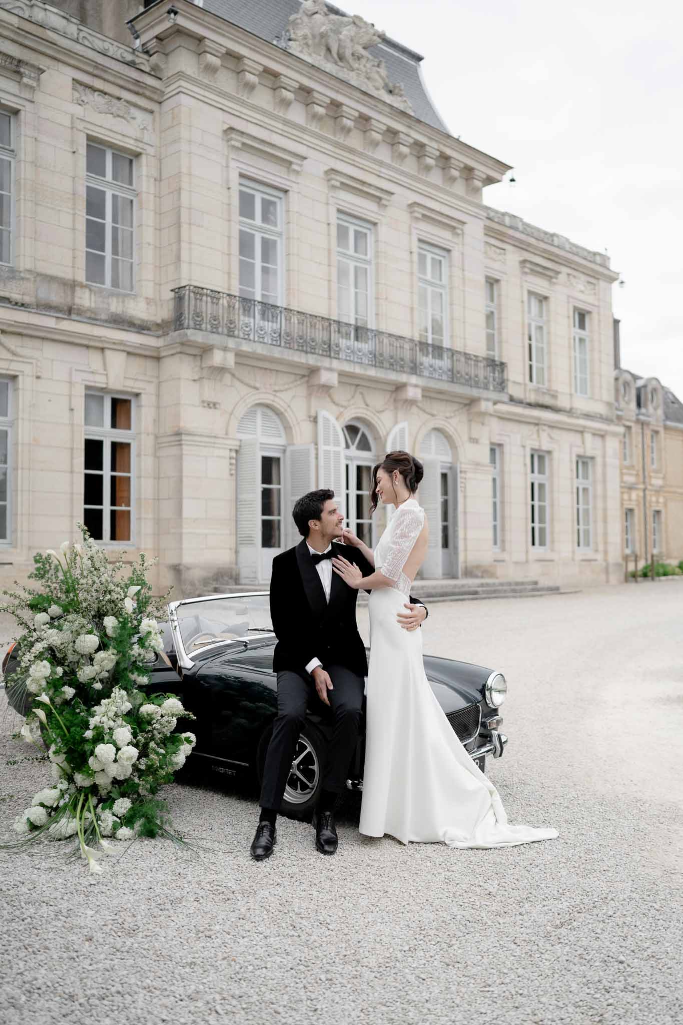 Couple in a tender embrace near the vintage car on the chateau grounds