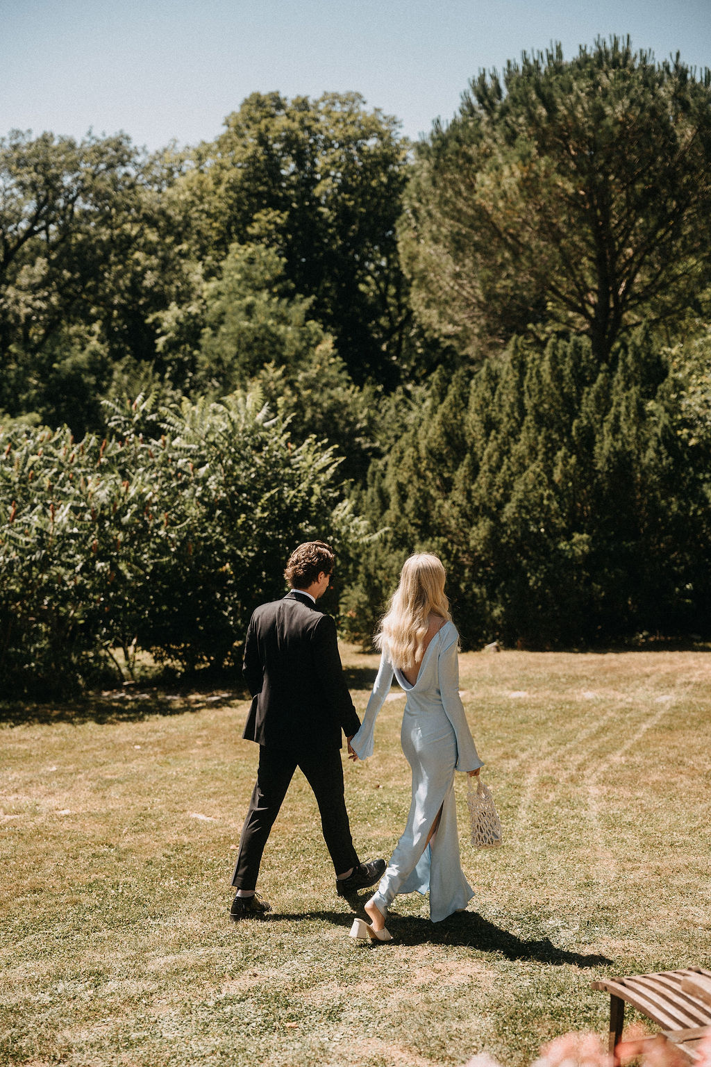 Bride and groom walking hand in hand in a garden