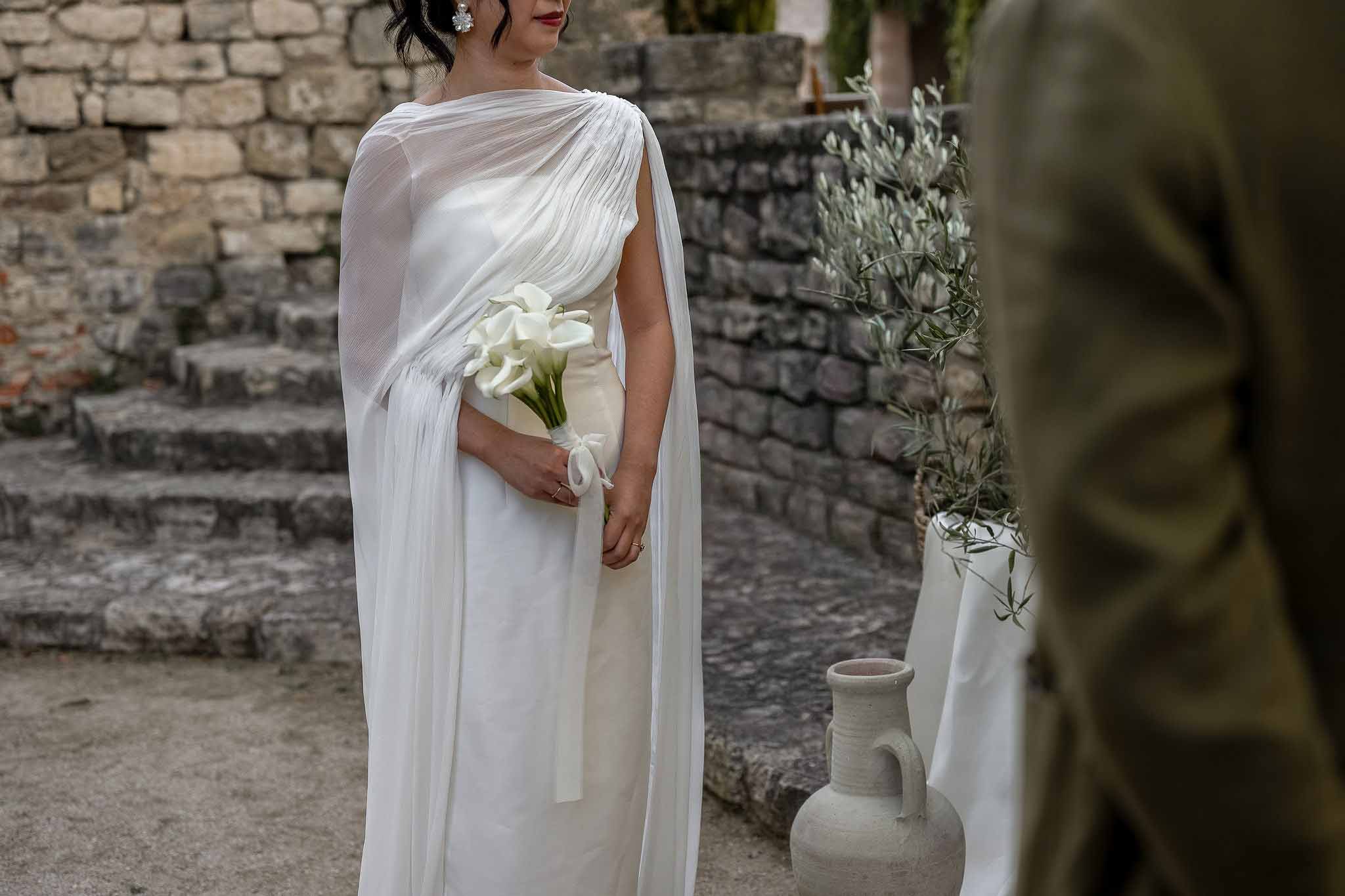 Close up of bride holding calla lily bouquet tied with white ribbon at ceremony altar