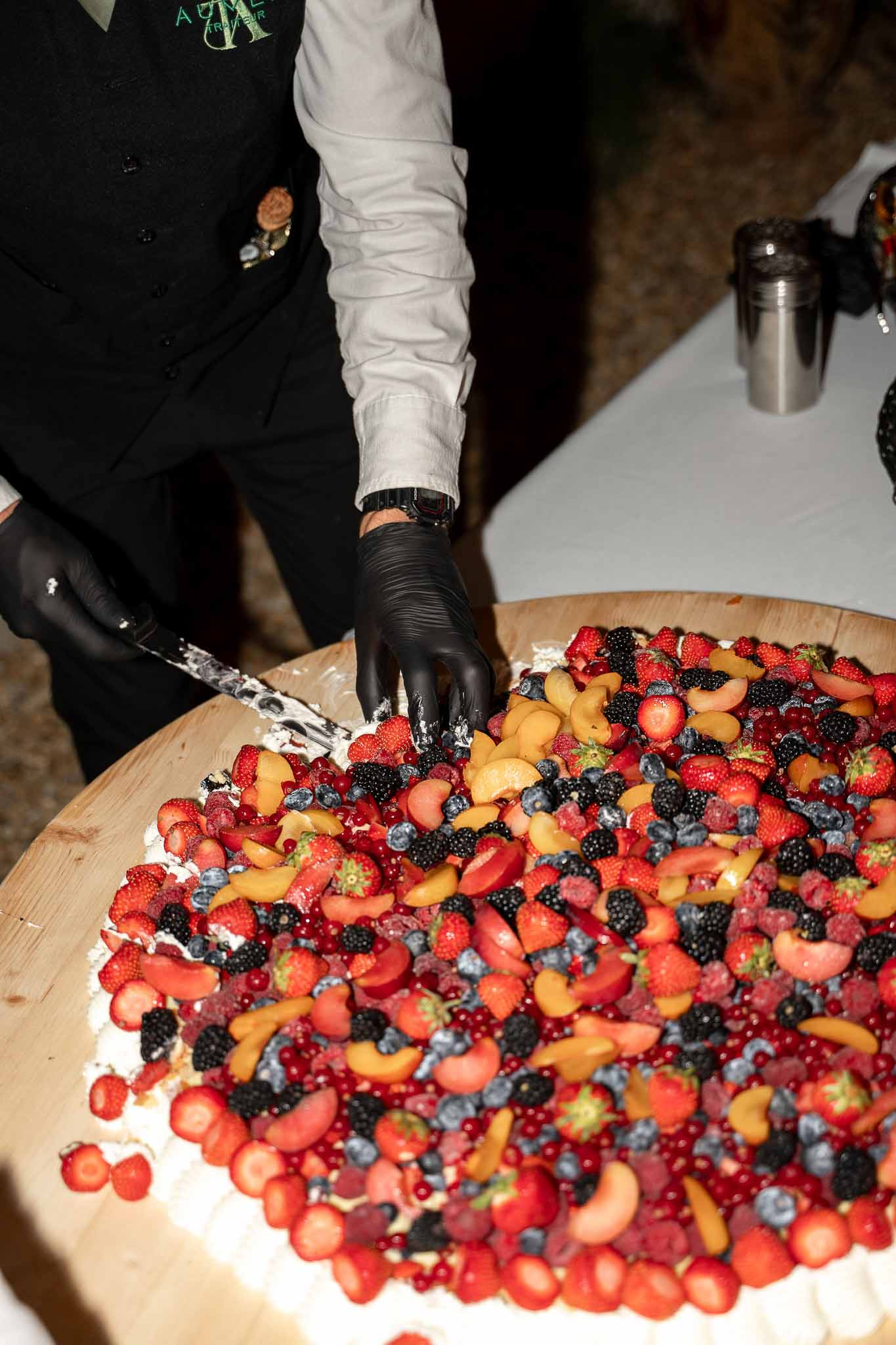 Waiter slicing wedding cake at the reception dinner table