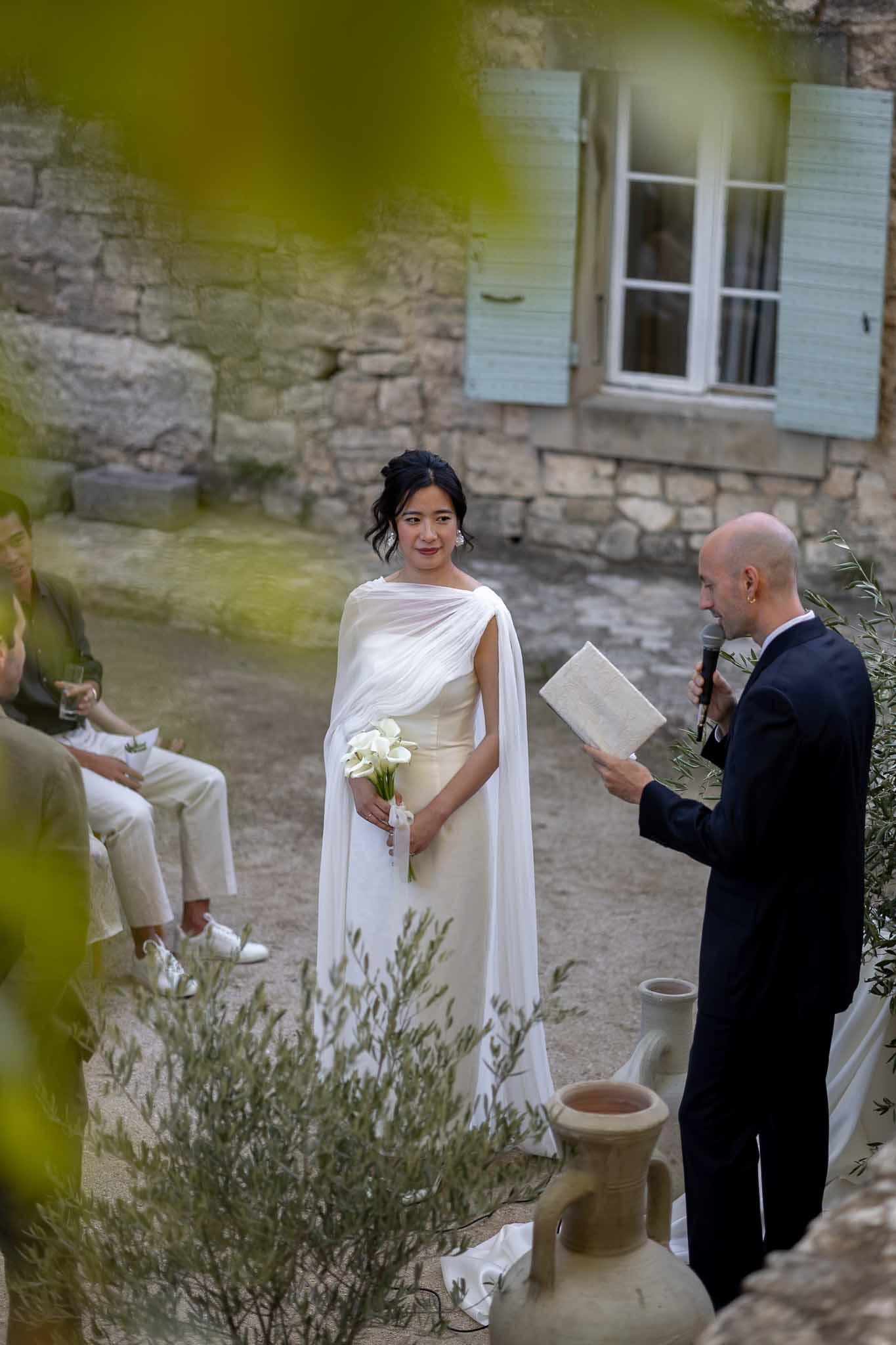 Officiant speaking with couple at olive branch arch altar during outdoor garden ceremony