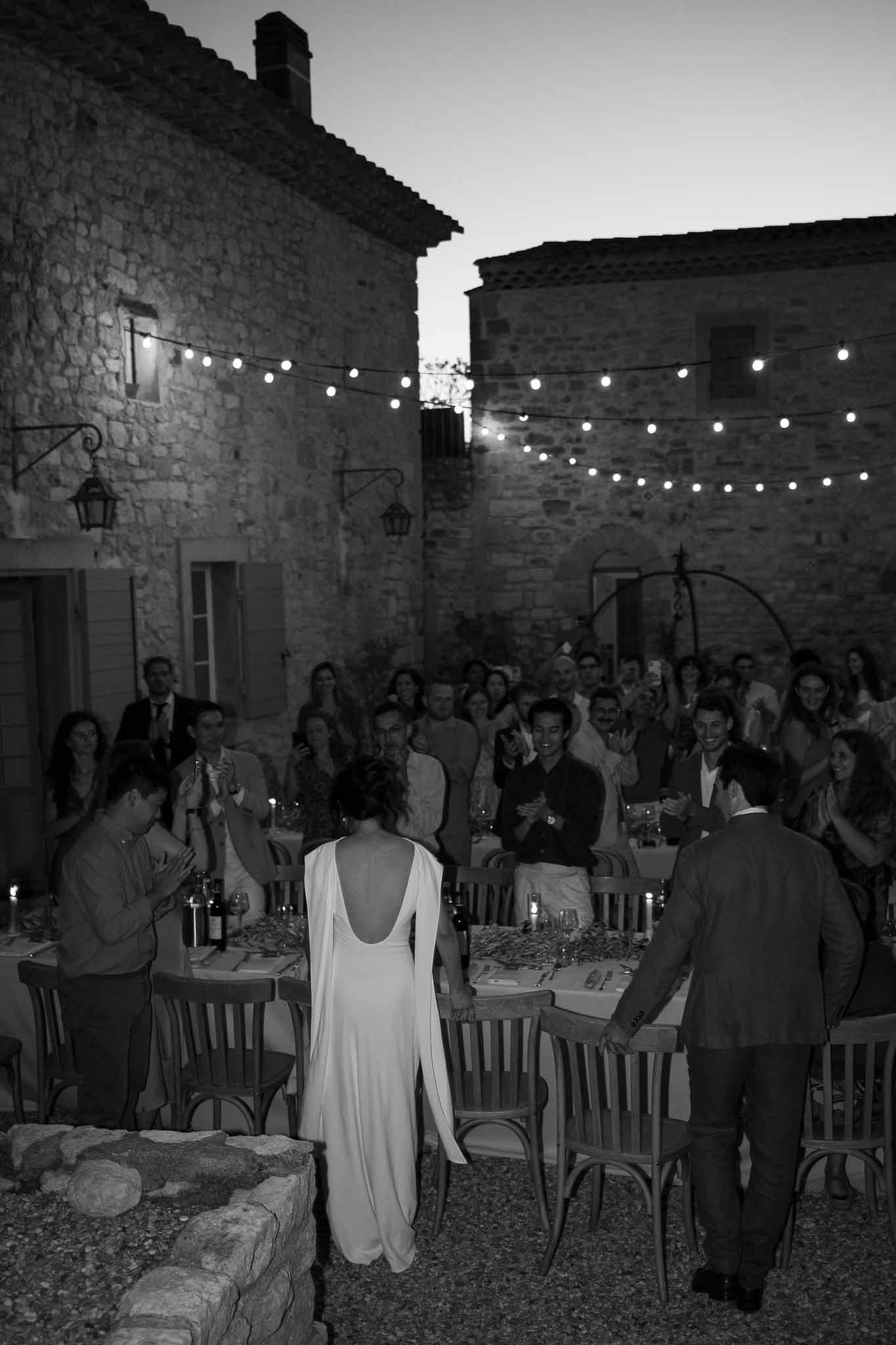 Couple mingling with guests at candlelit outdoor reception dinner under string lights