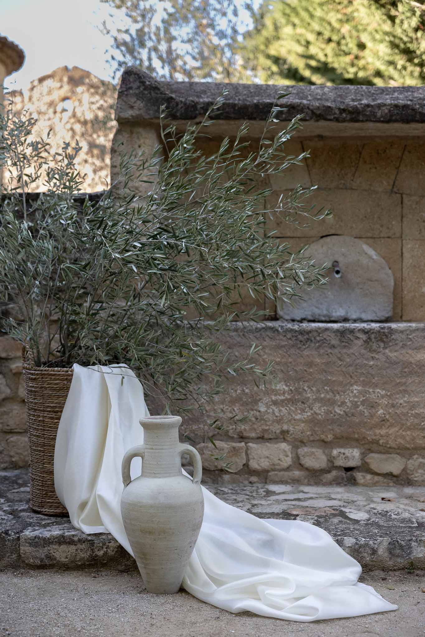 Vintage vase with simple green floral arrangement against stone brick wall