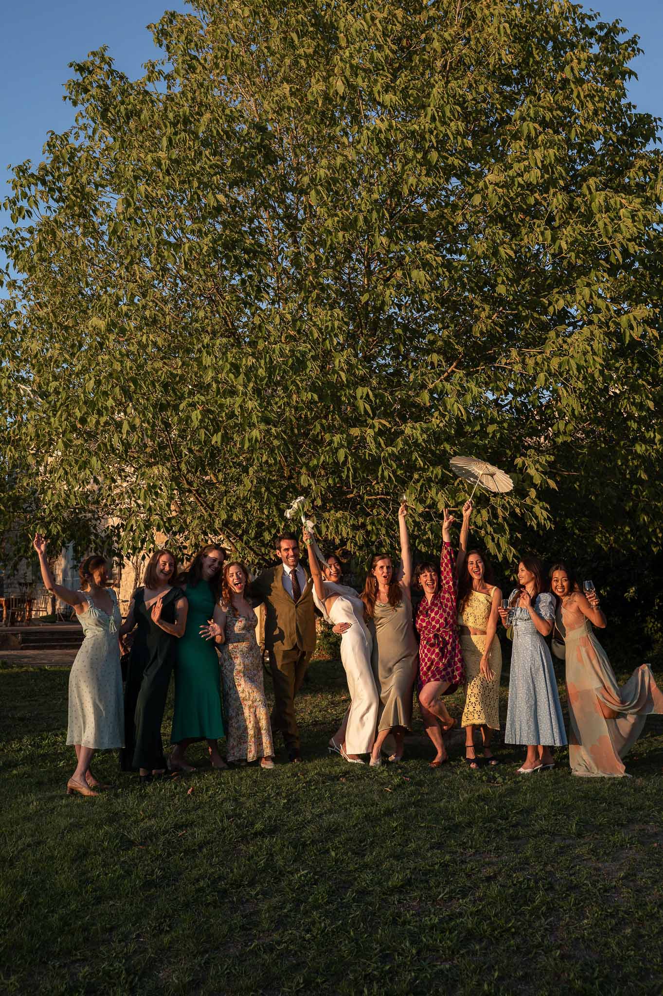 Bridal party gathered together in garden at Notre-Dame de Conil during golden hour