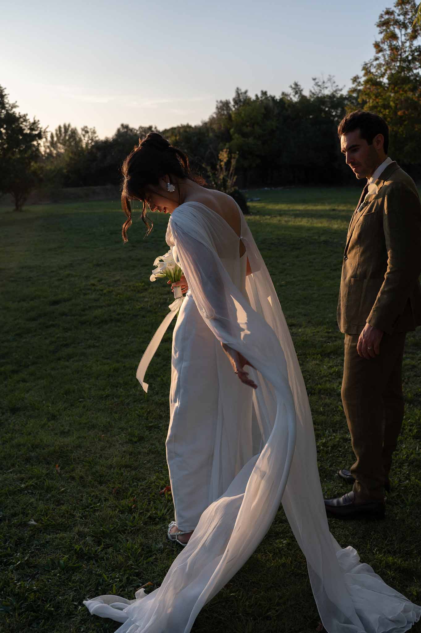 Bride and groom walking hand in hand through garden in golden hour light