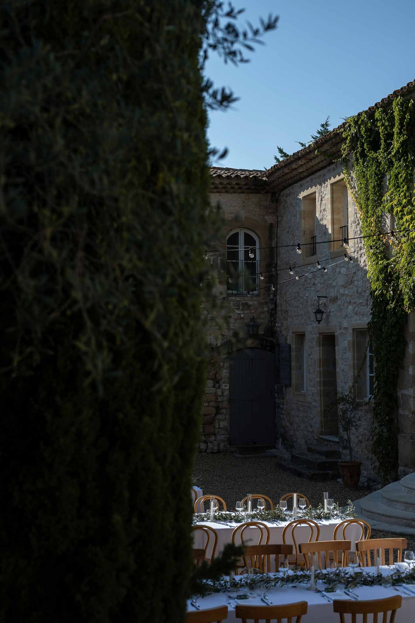 Elegant reception tablescape with olive branch centrepieces against vintage Provençal stone wall