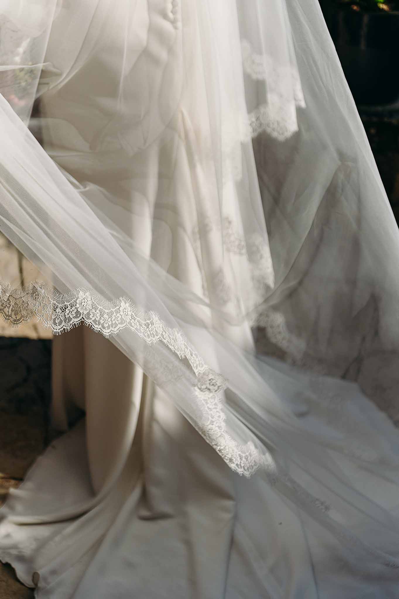 Close-up of bride's lace dress trim and long veil at Domaine de Perrotin