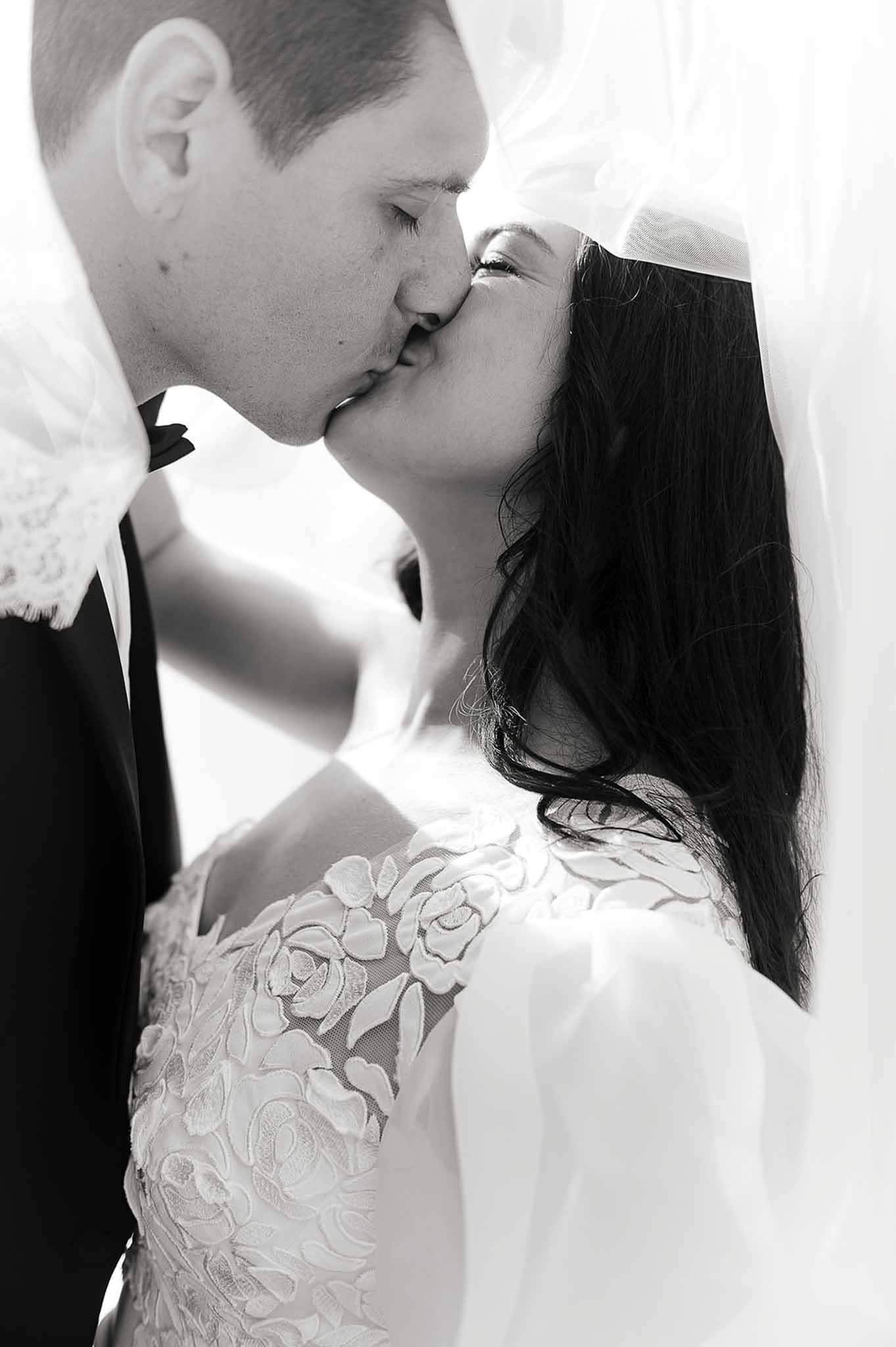 Black and white photo of couple kissing inside the bride's veil at Domaine de Perrotin