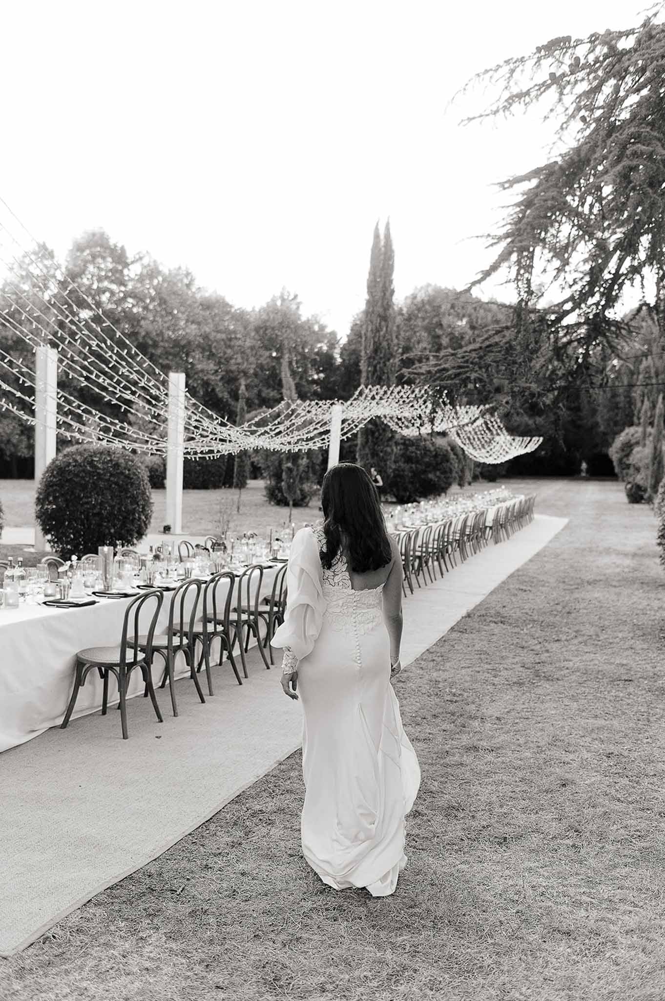Black and white photo of bride walking through the reception garden at Domaine de Perrotin