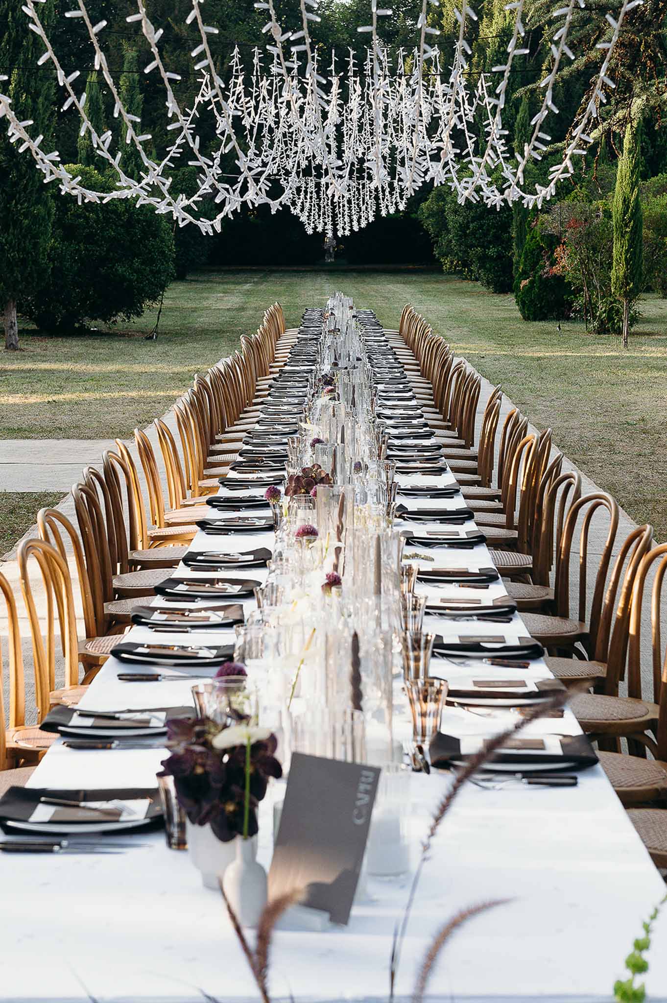 Reception centrepiece with glasses, candles, string lights and chandelier at Domaine de Perrotin