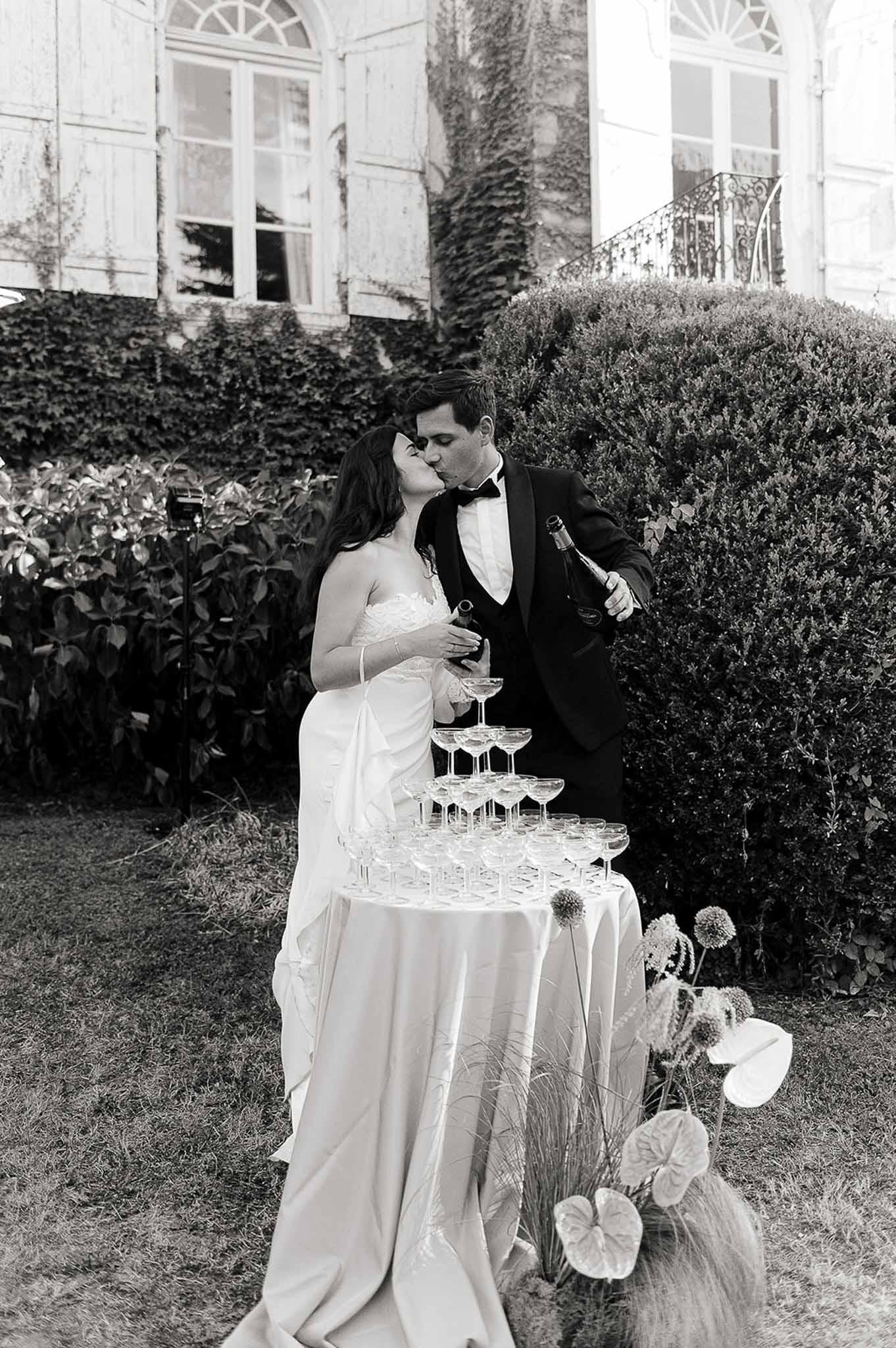 Couple kissing beside a champagne glass tower at Domaine de Perrotin