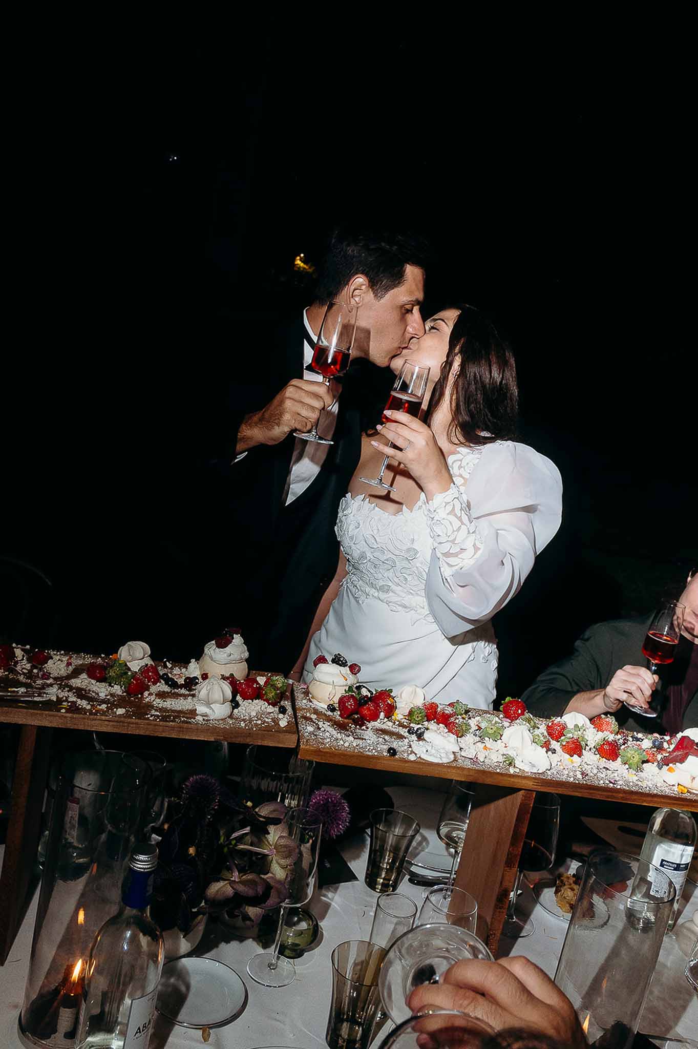 Couple kissing at the cake table during the reception dinner at Domaine de Perrotin