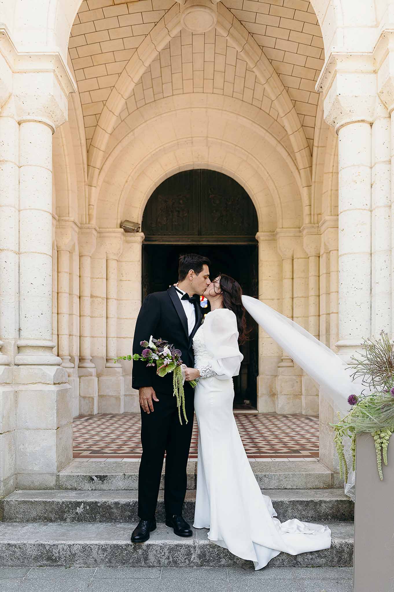 Couple kissing at the entrance door of the church at Domaine de Perrotin