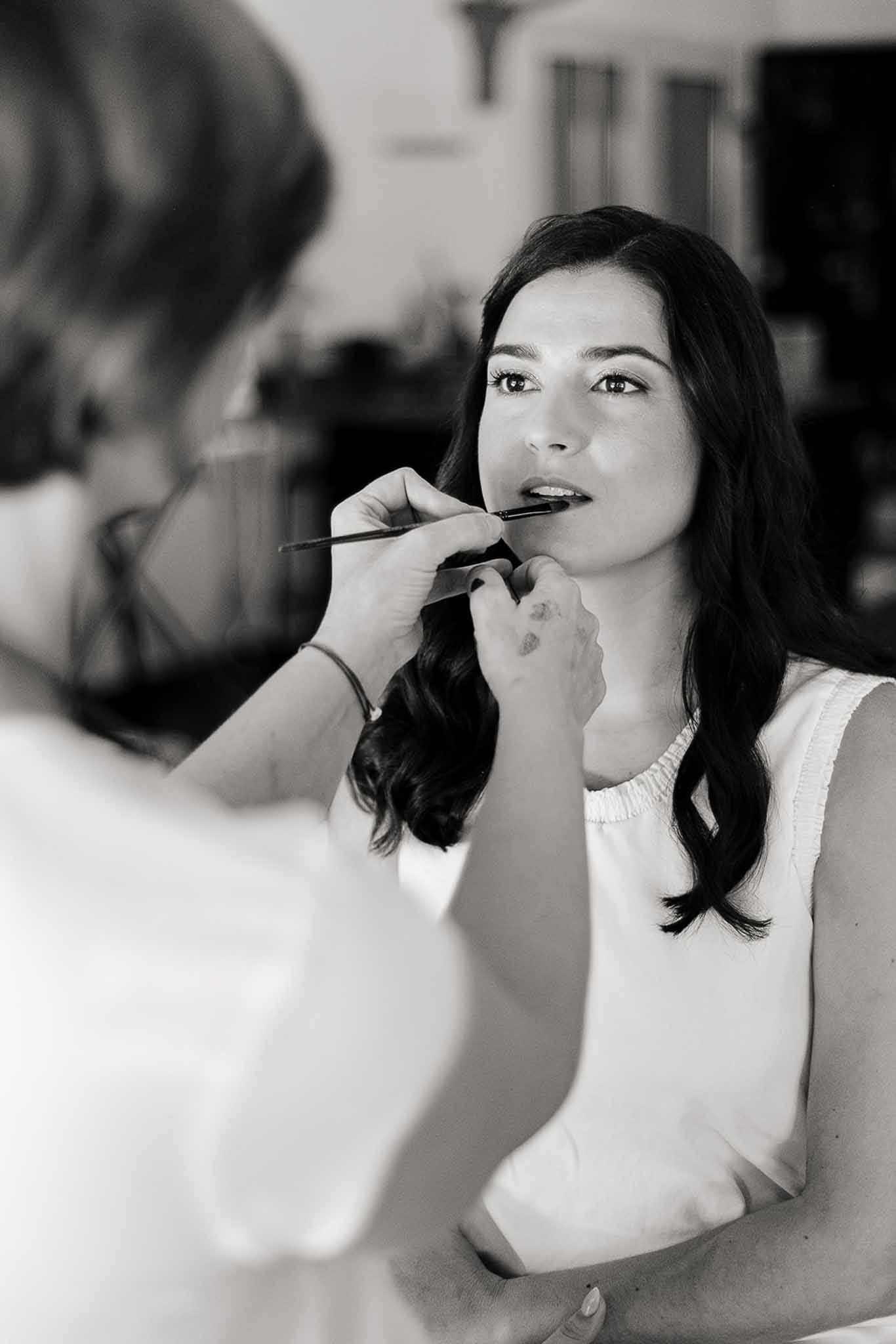 Bride seated in a chair with lipstick during getting ready at Domaine de Perrotin