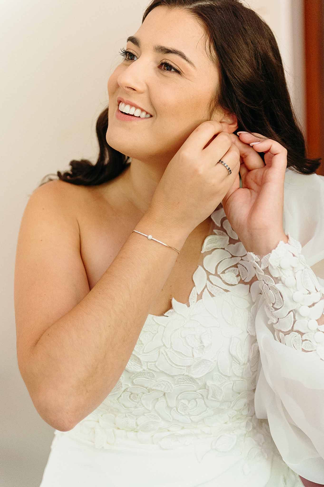 Bride putting on earrings during getting ready at Domaine de Perrotin