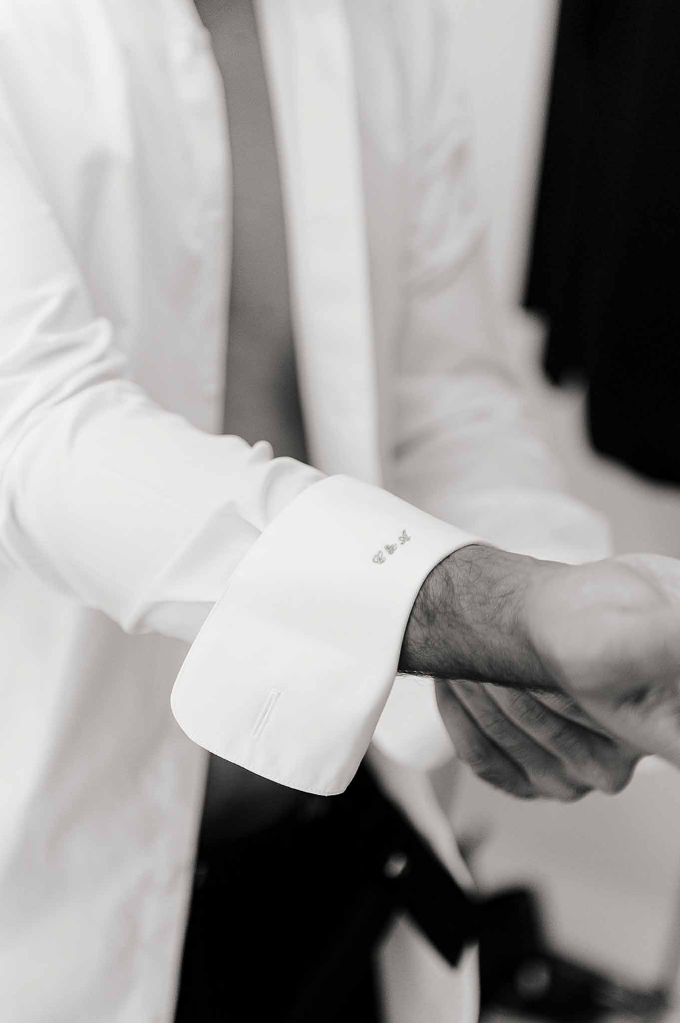 Groom adjusting tuxedo cufflinks during getting ready at Domaine de Perrotin