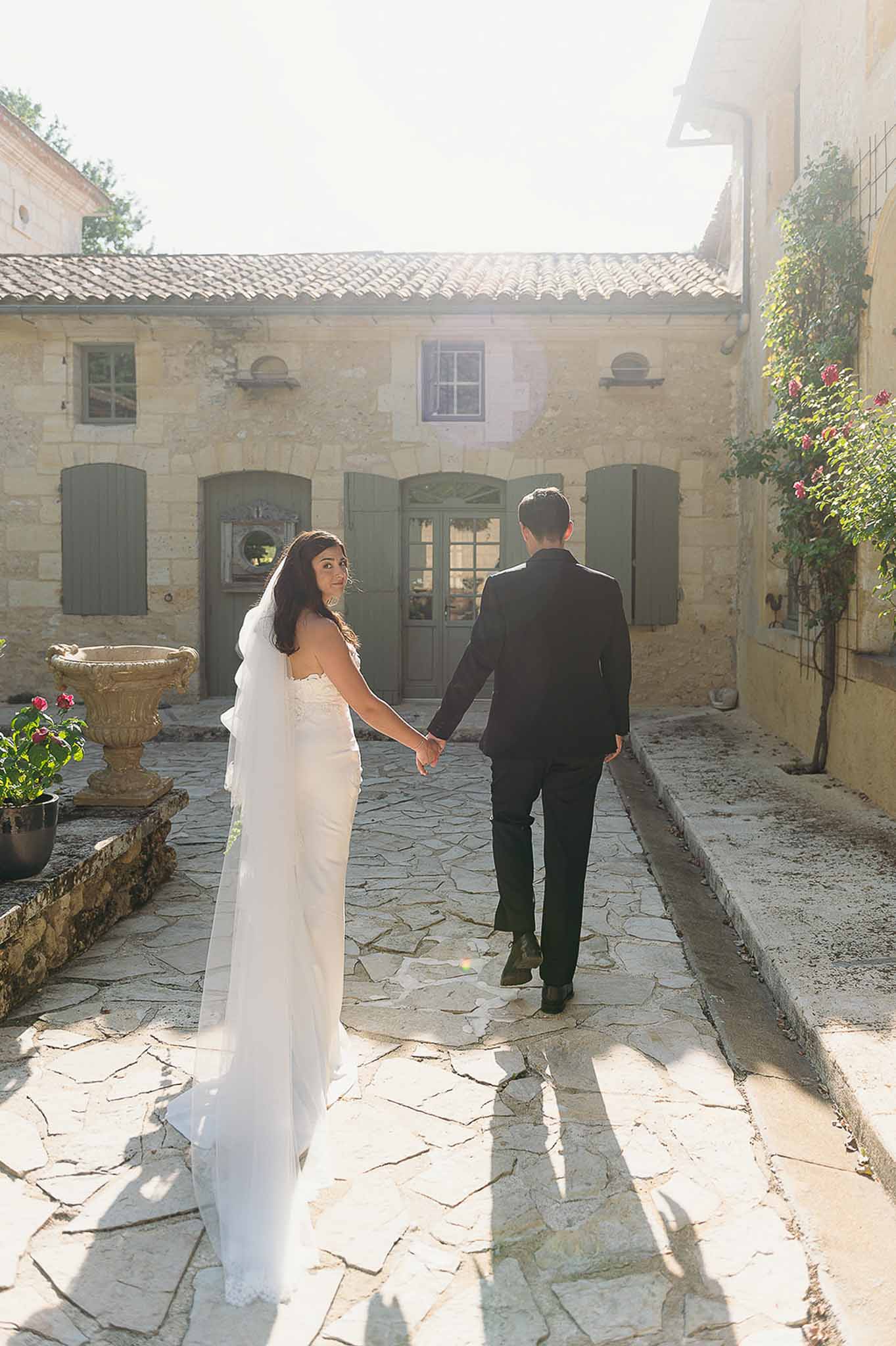 Bride and groom holding hands and walking during golden hour at Domaine de Perrotin