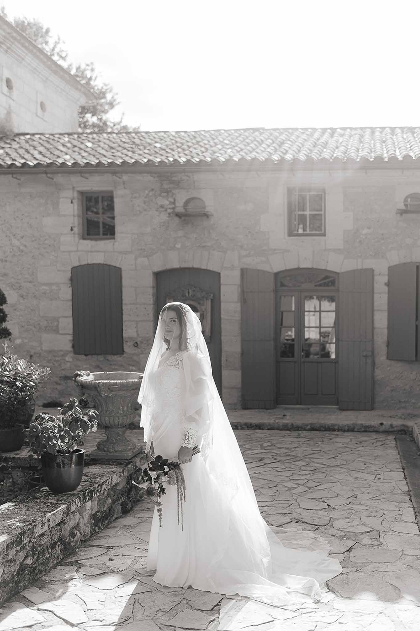 Bride in a long lace dress with flowing veil during golden hour at Domaine de Perrotin