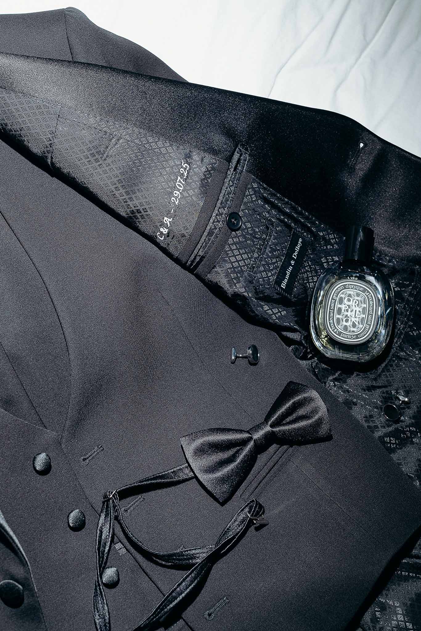 Groom's black suit accessories and perfume flat lay at Domaine de Perrotin