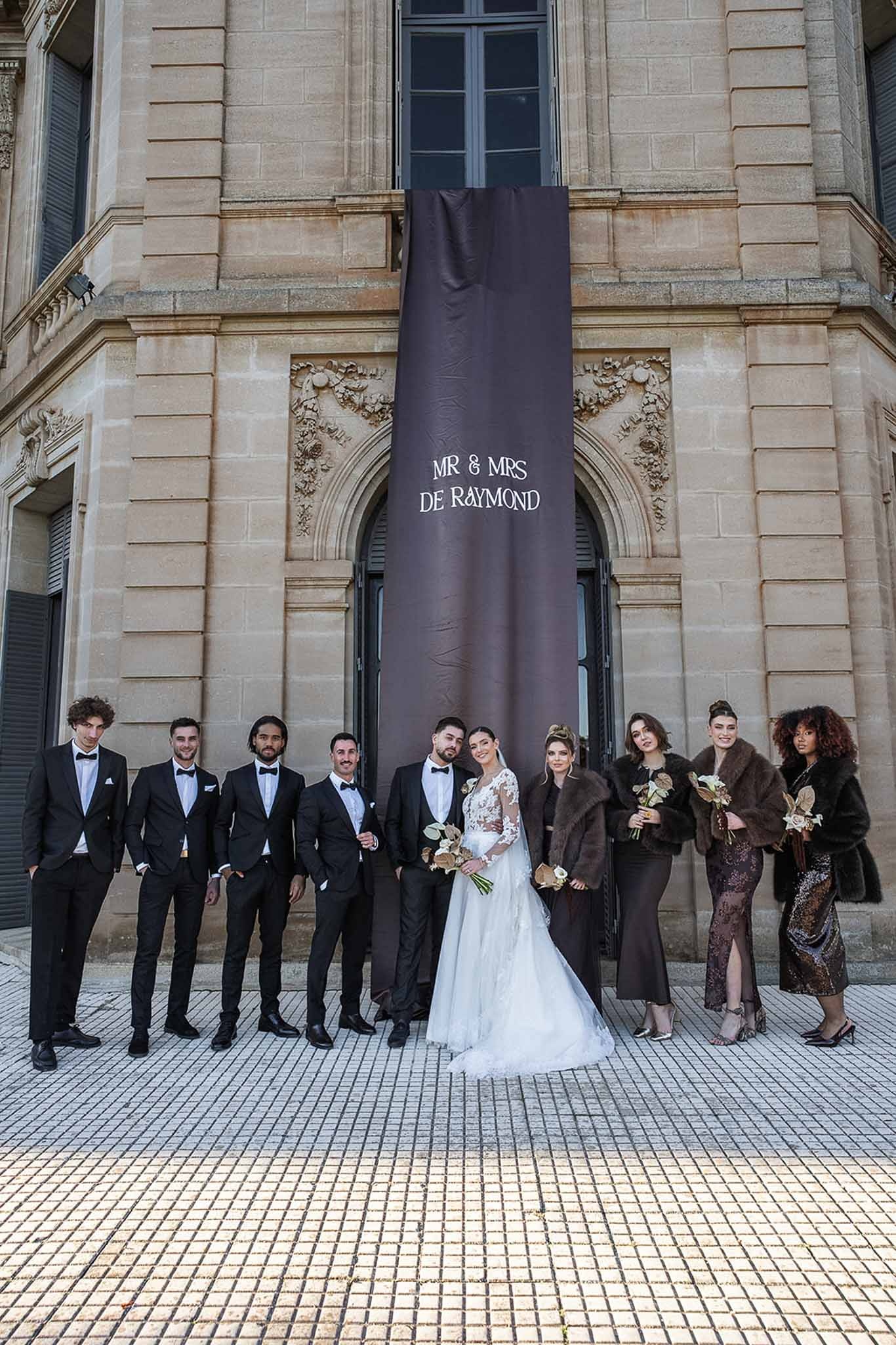 Bridal party portrait at Chateau du Terral with dramatic black banner