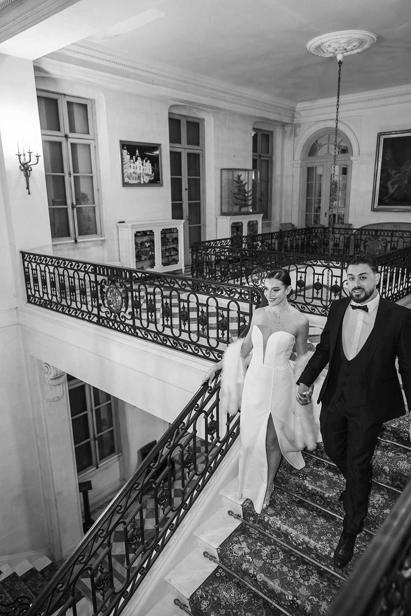 Couple descending grand staircase at Chateau du Terral in black and white