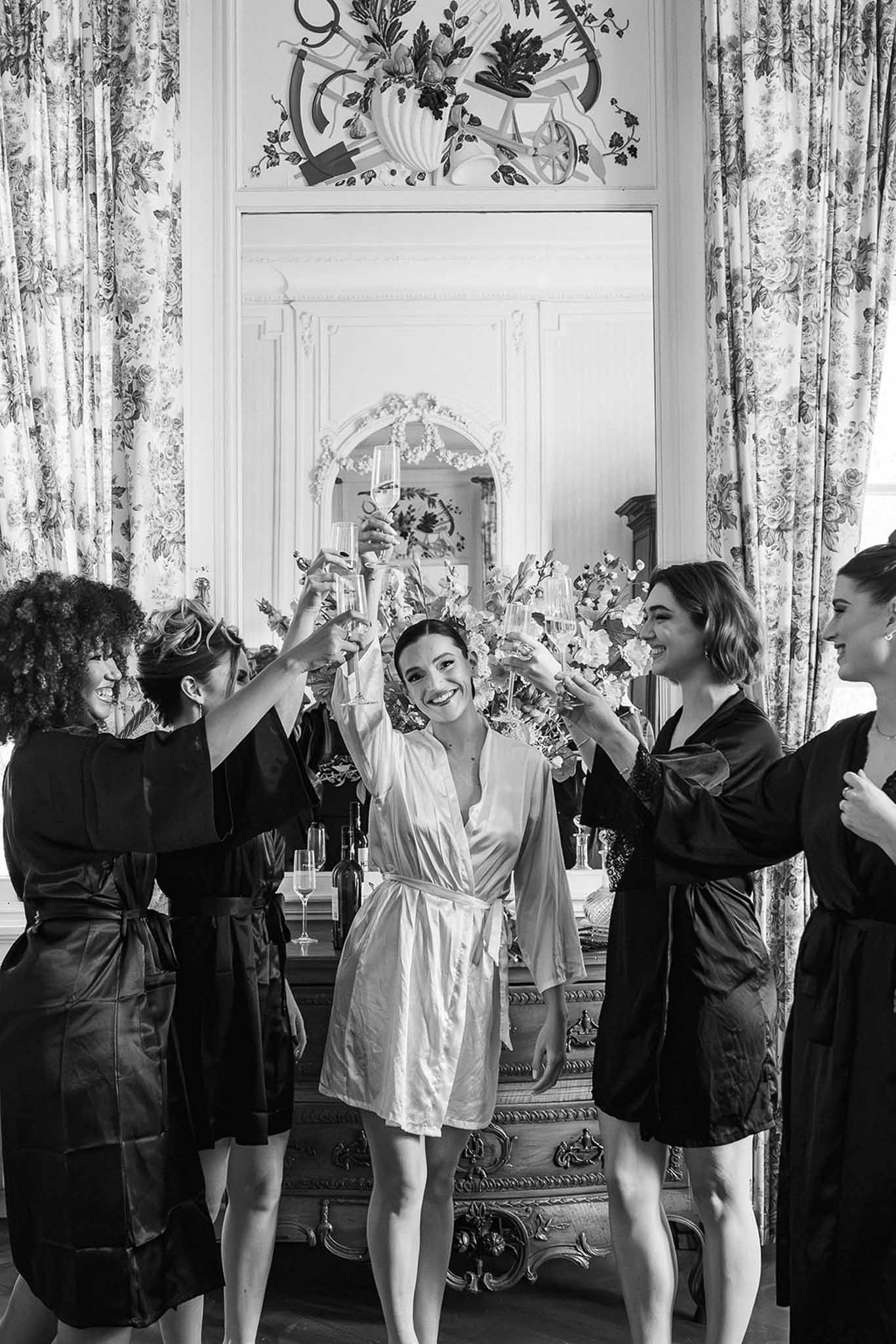 Bride in silk robe with bridesmaids toasting champagne at Chateau du Terral