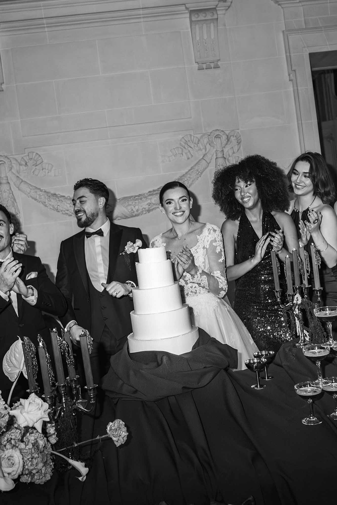 Couple with four-tier wedding cake and friends at Chateau du Terral reception
