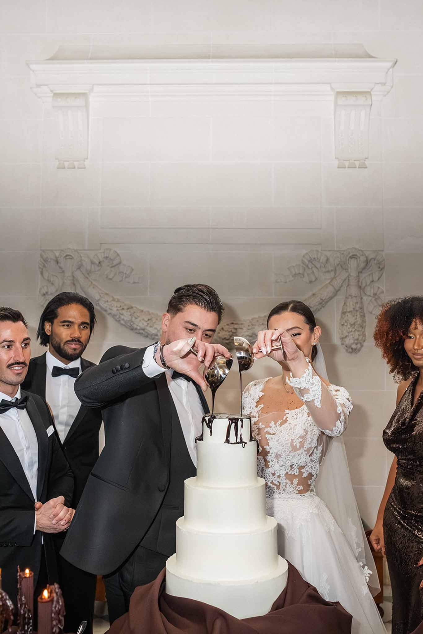 Couple pouring chocolate over four-tier wedding cake at Chateau du Terral reception