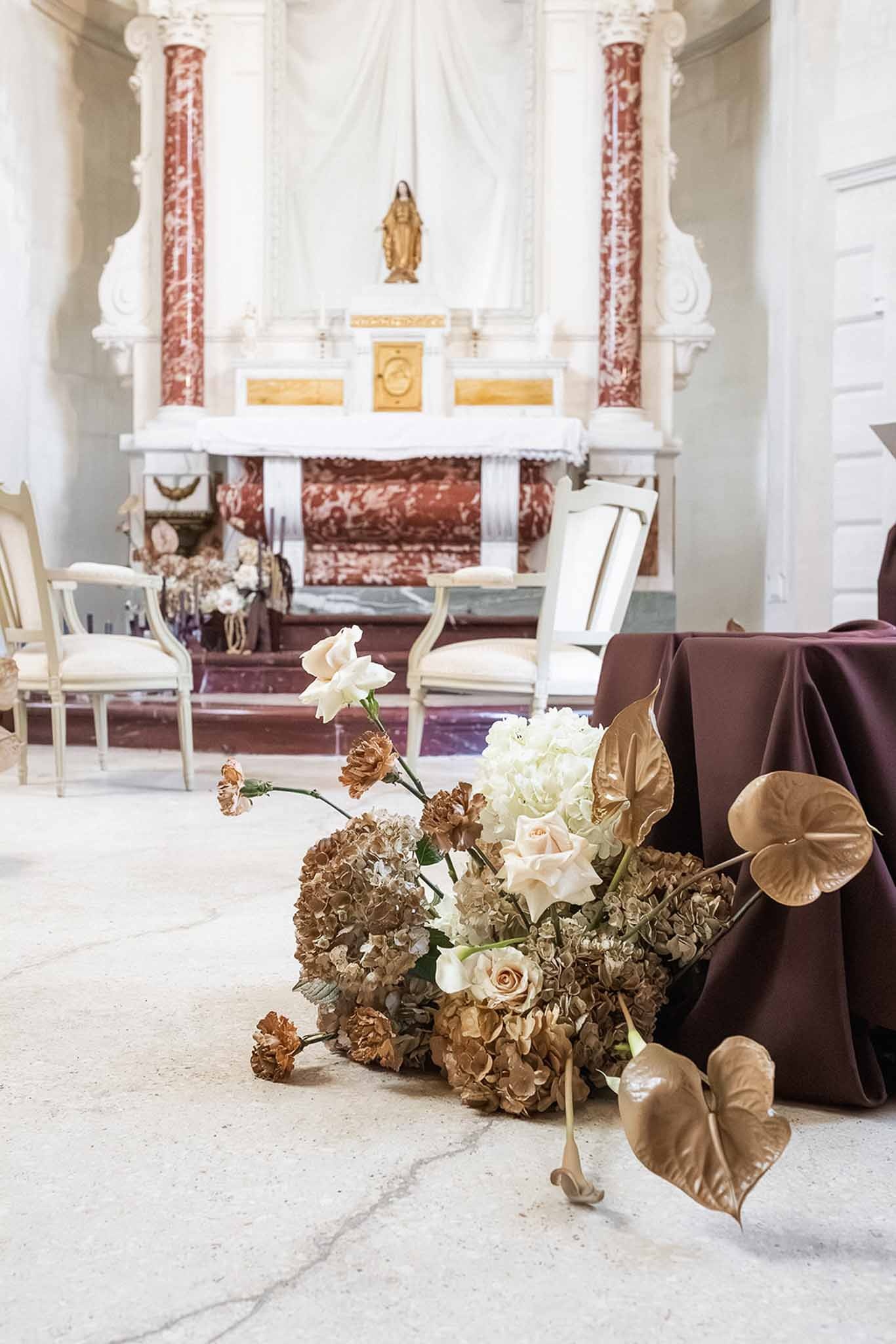 Chapel aisle dried floral arrangement with gold anthurium at Chateau du Terral
