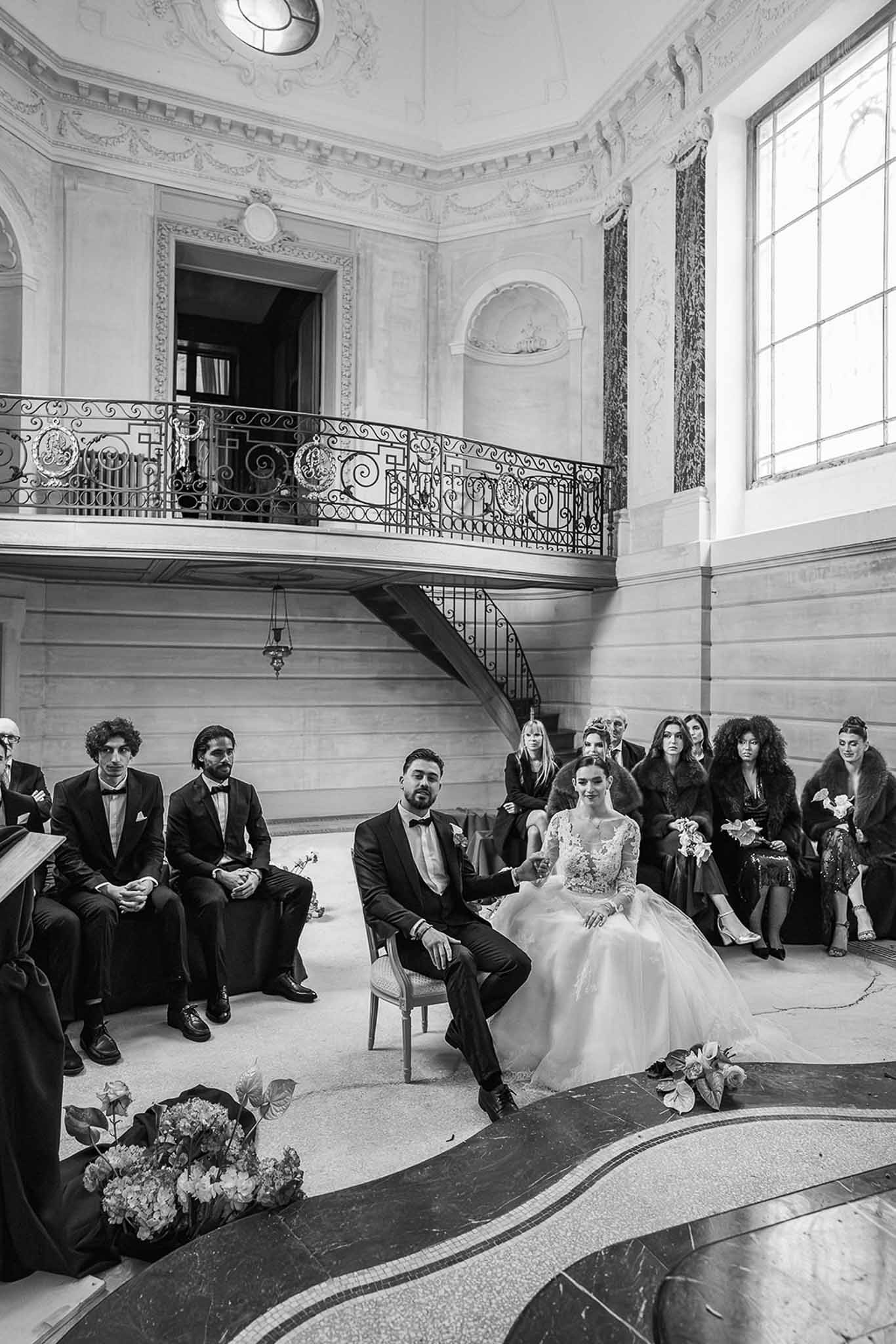 Couple with bridal party during ceremony in grand hall at Chateau du Terral
