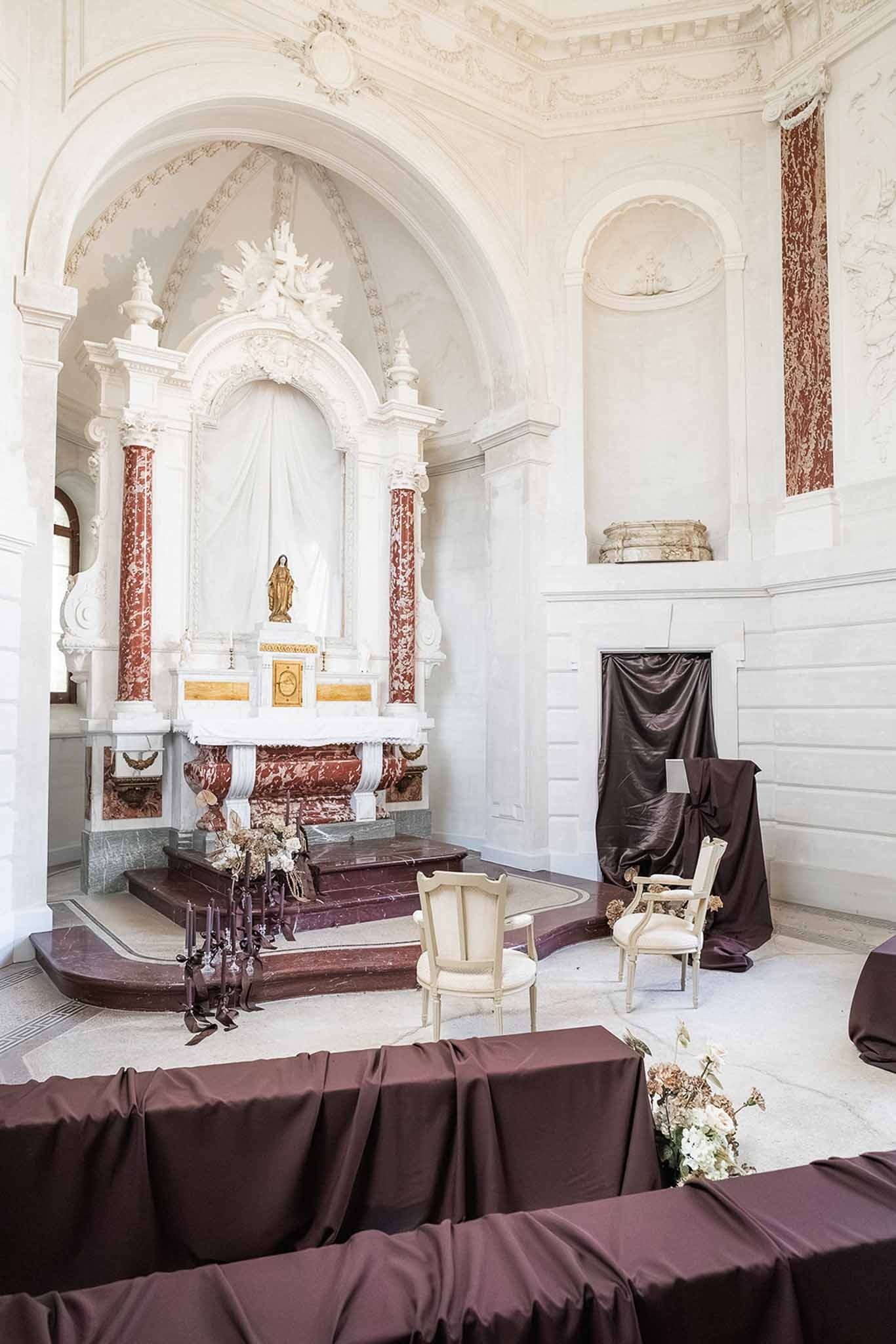 Chapel ceremony setup with baroque altar and dark draping at Chateau du Terral