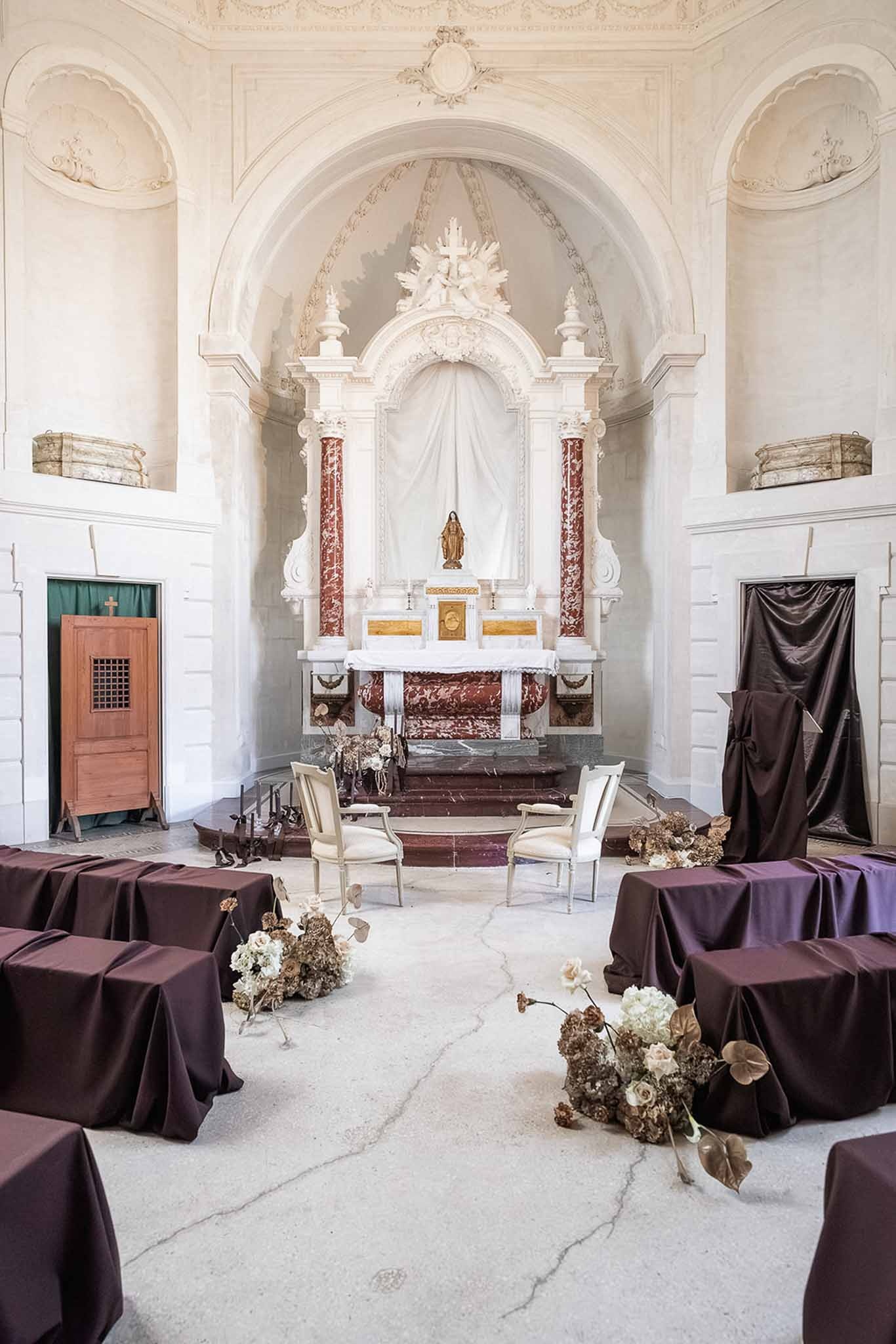Chapel interior with dark-draped pews and dried florals at Chateau du Terral