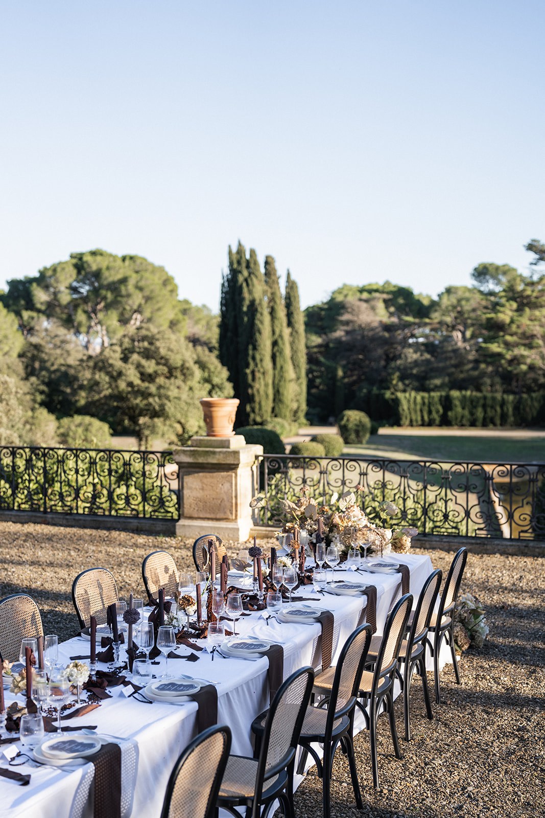 Long reception table set on chateau terrace with cypress garden backdrop at Chateau du Terral