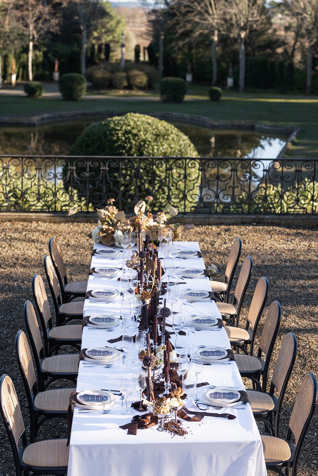 Reception table with brown candles overlooking ornamental pond at Chateau du Terral
