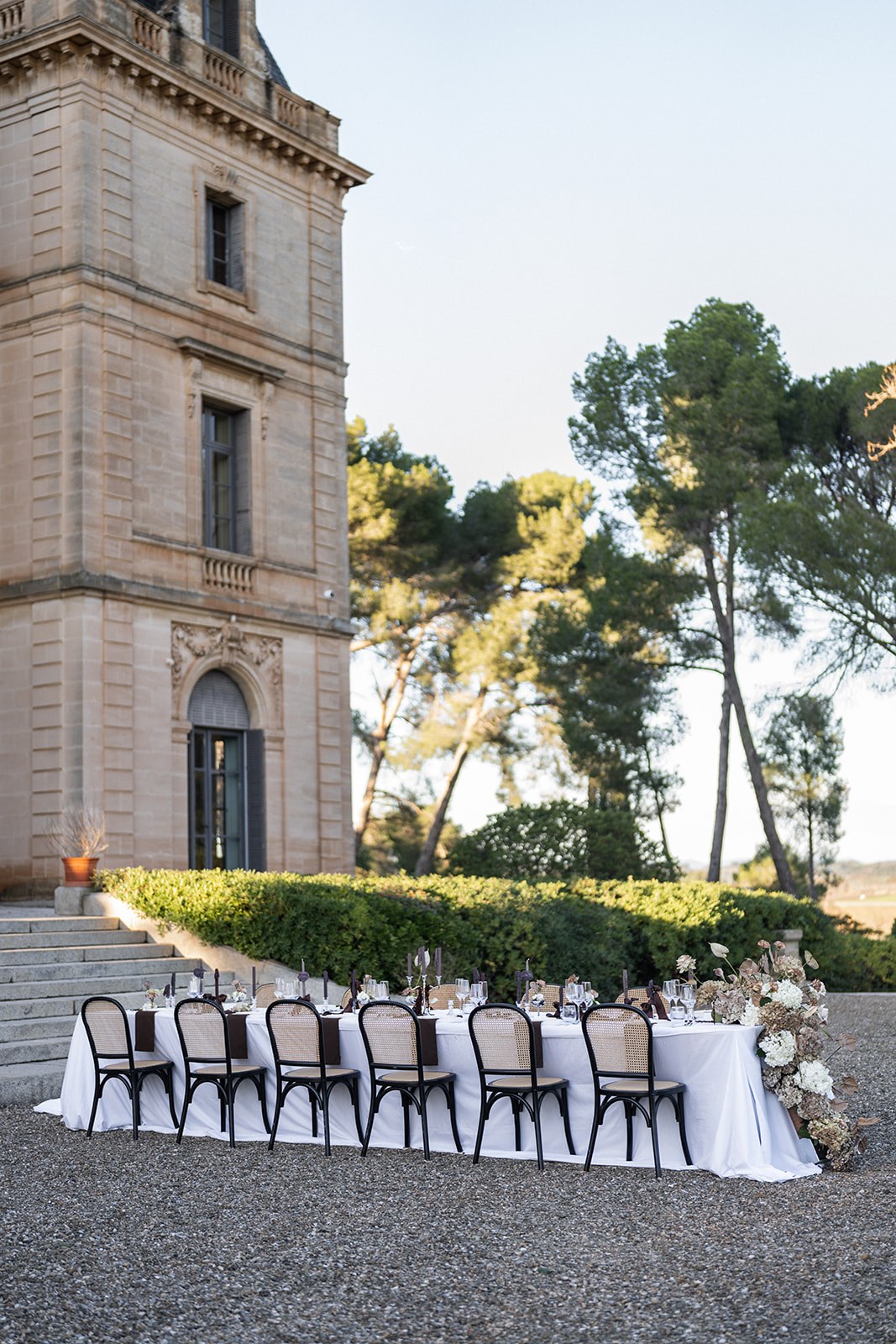 Reception table set beside chateau tower with hedge backdrop at Chateau du Terral