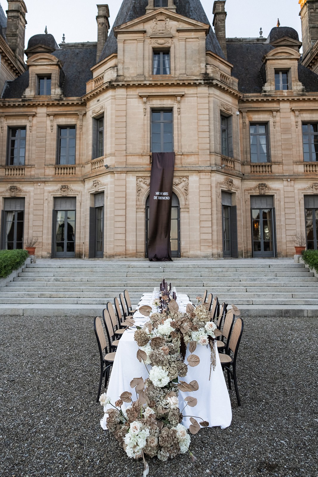 Reception table with cascading florals before chateau facade at Chateau du Terral wedding