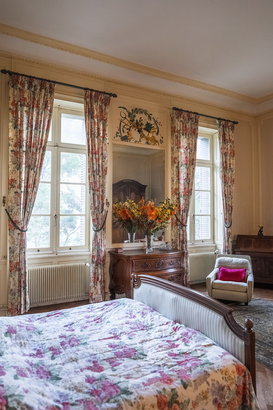 Chateau guest bedroom with floral curtains and antique armoire at Chateau du Terral
