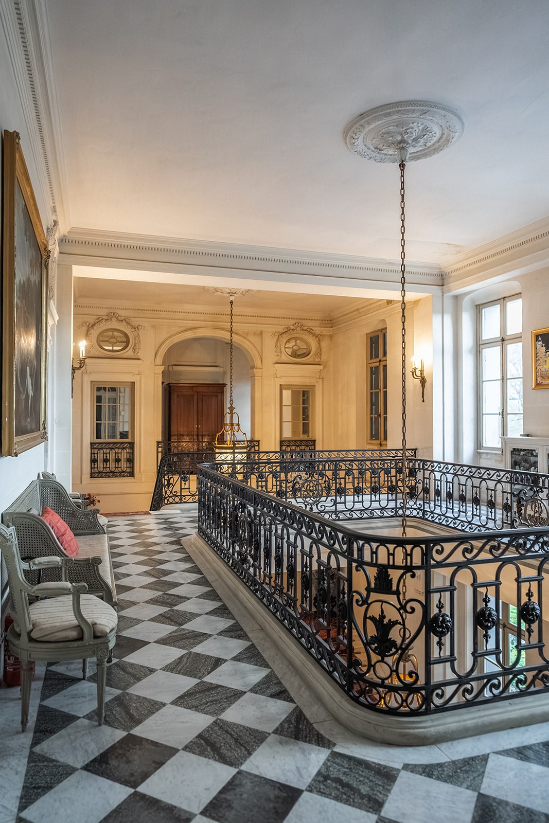 Upper landing with checkerboard marble floor and wrought iron balustrade at Chateau du Terral