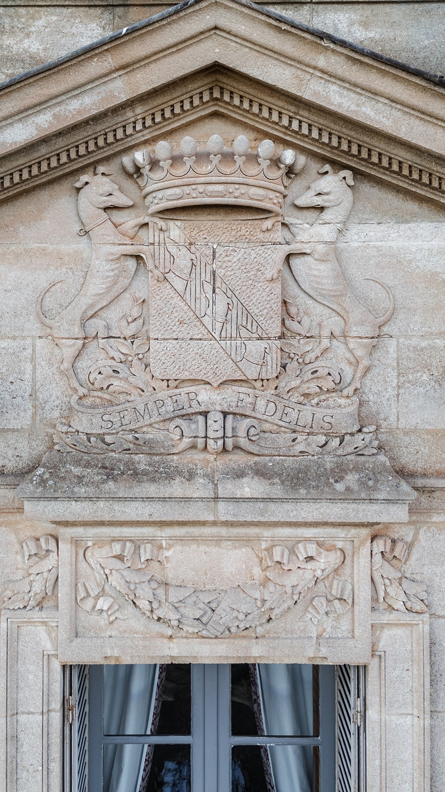 Carved stone family crest above chateau window at Chateau du Terral