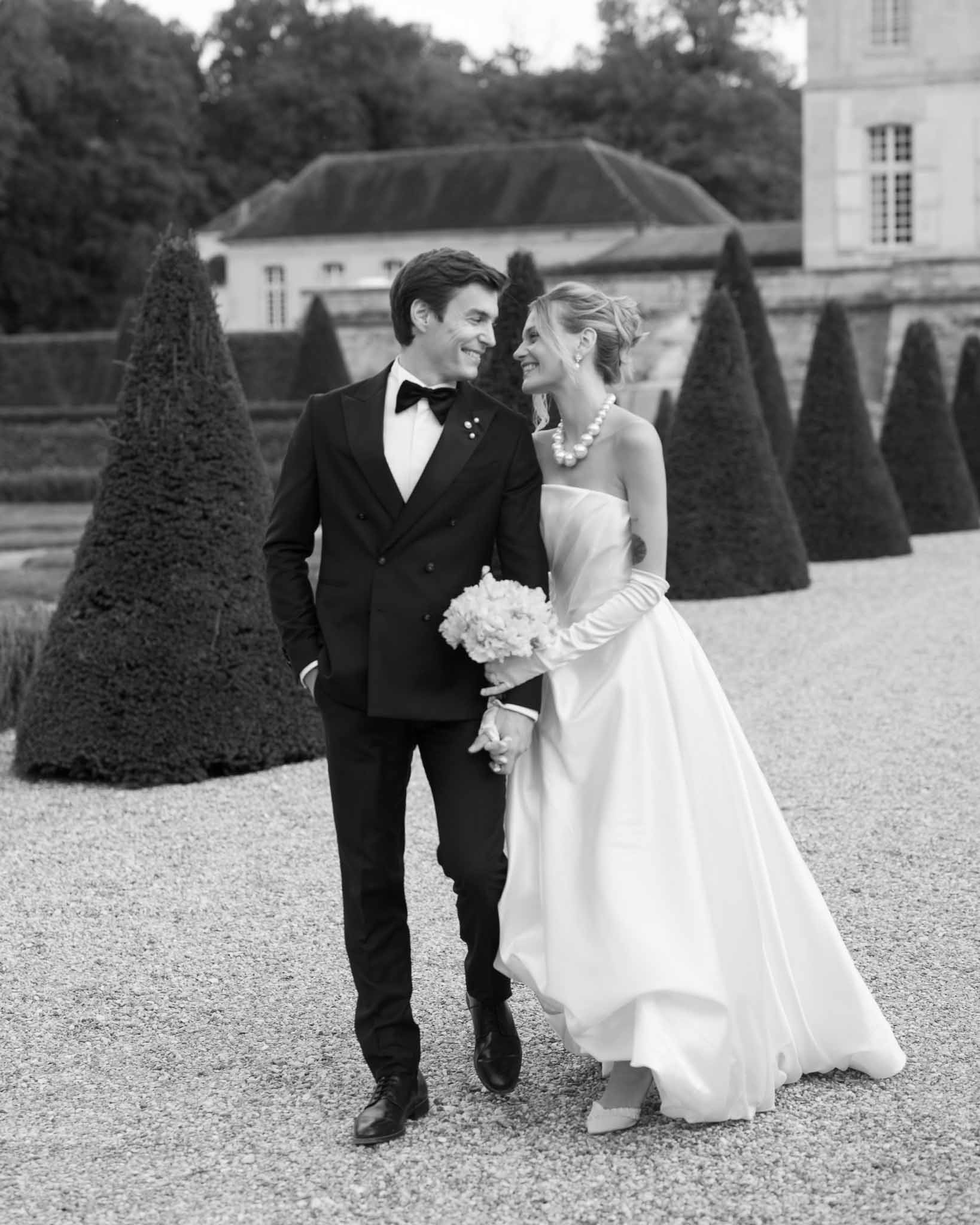 Bride holding pink hydrangea bouquet as groom hugs her from behind