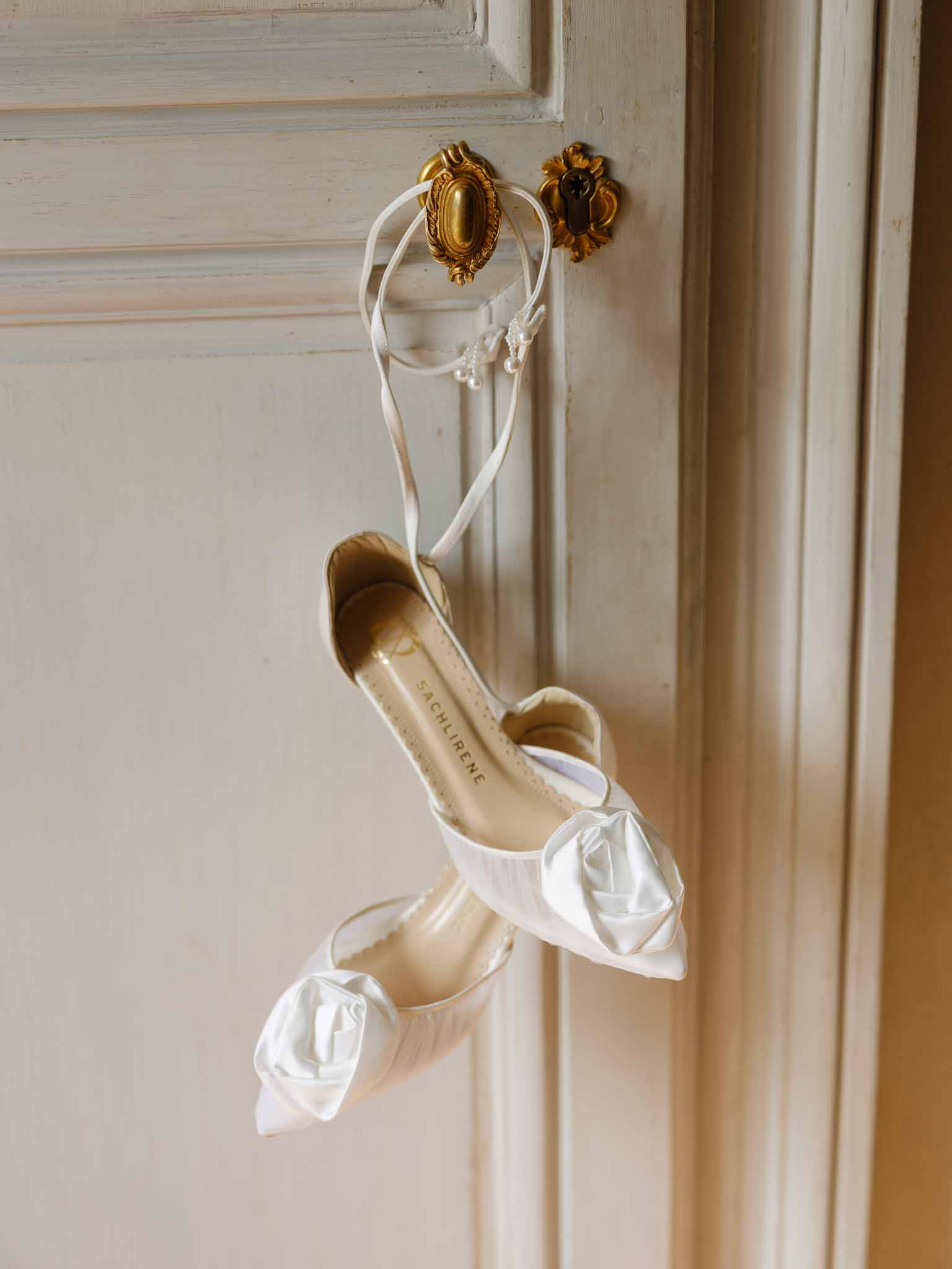 Bridal shoes hanging by their ribbons from a vintage door knob