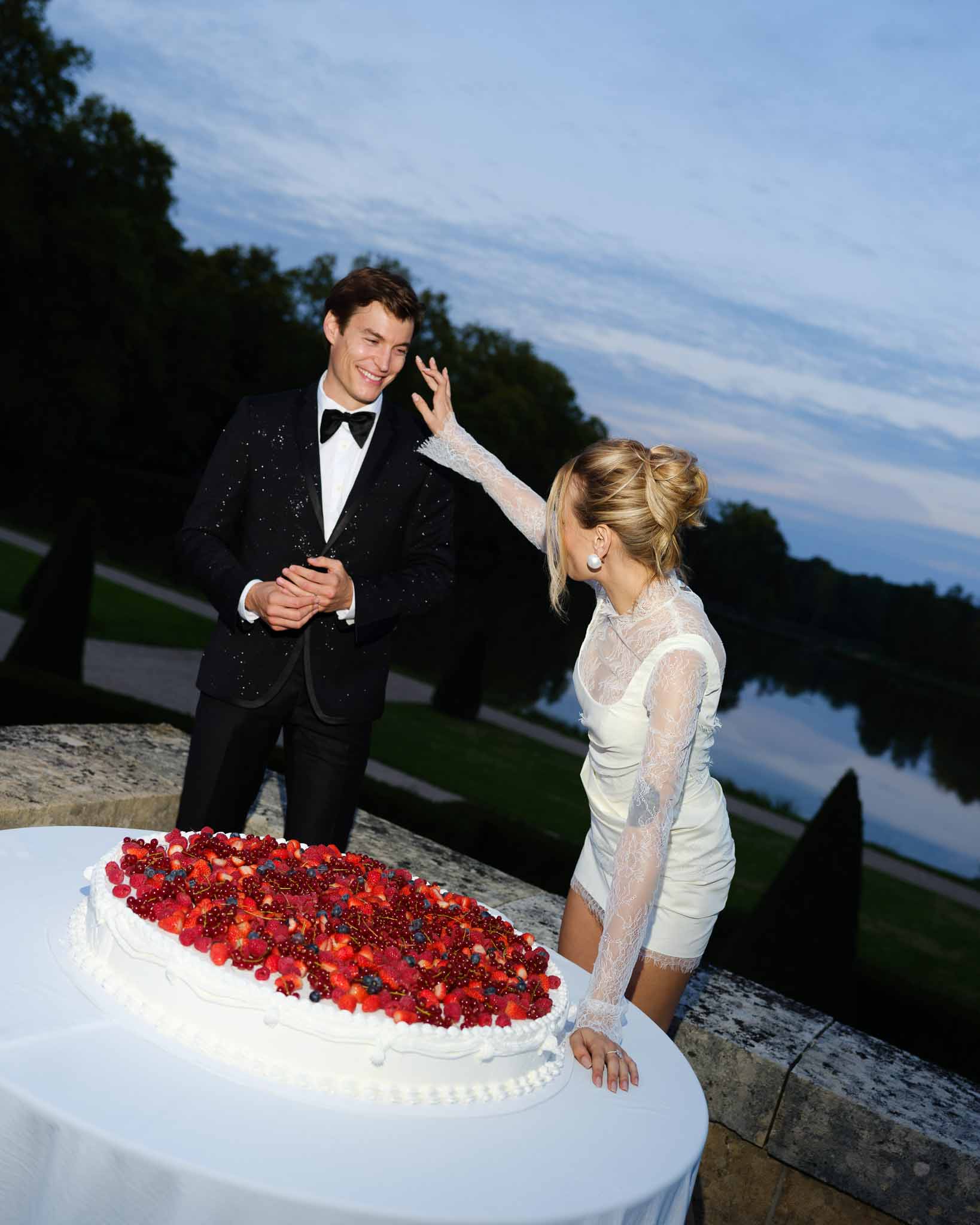Couple sharing cake at the reception as evening falls