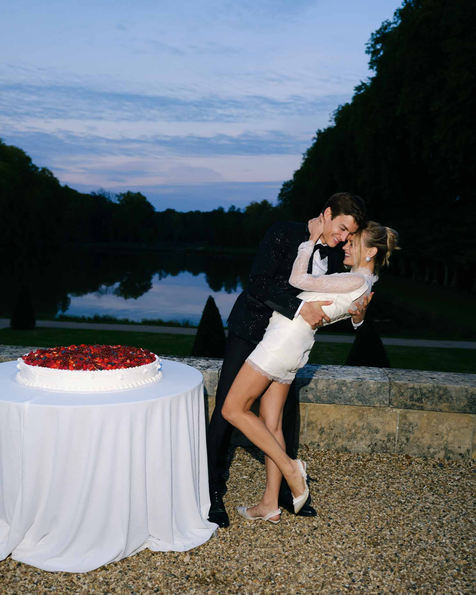 Couple sharing a kiss next to their strawberry wedding cake