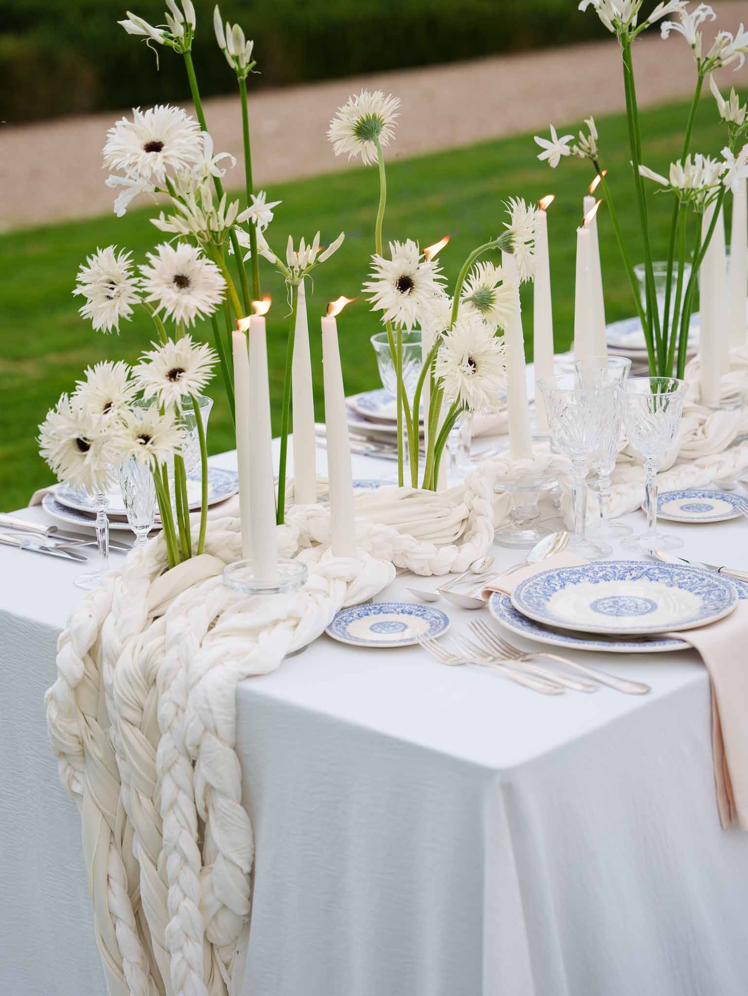Table centerpiece with loose florals, taper candles, and linen runner